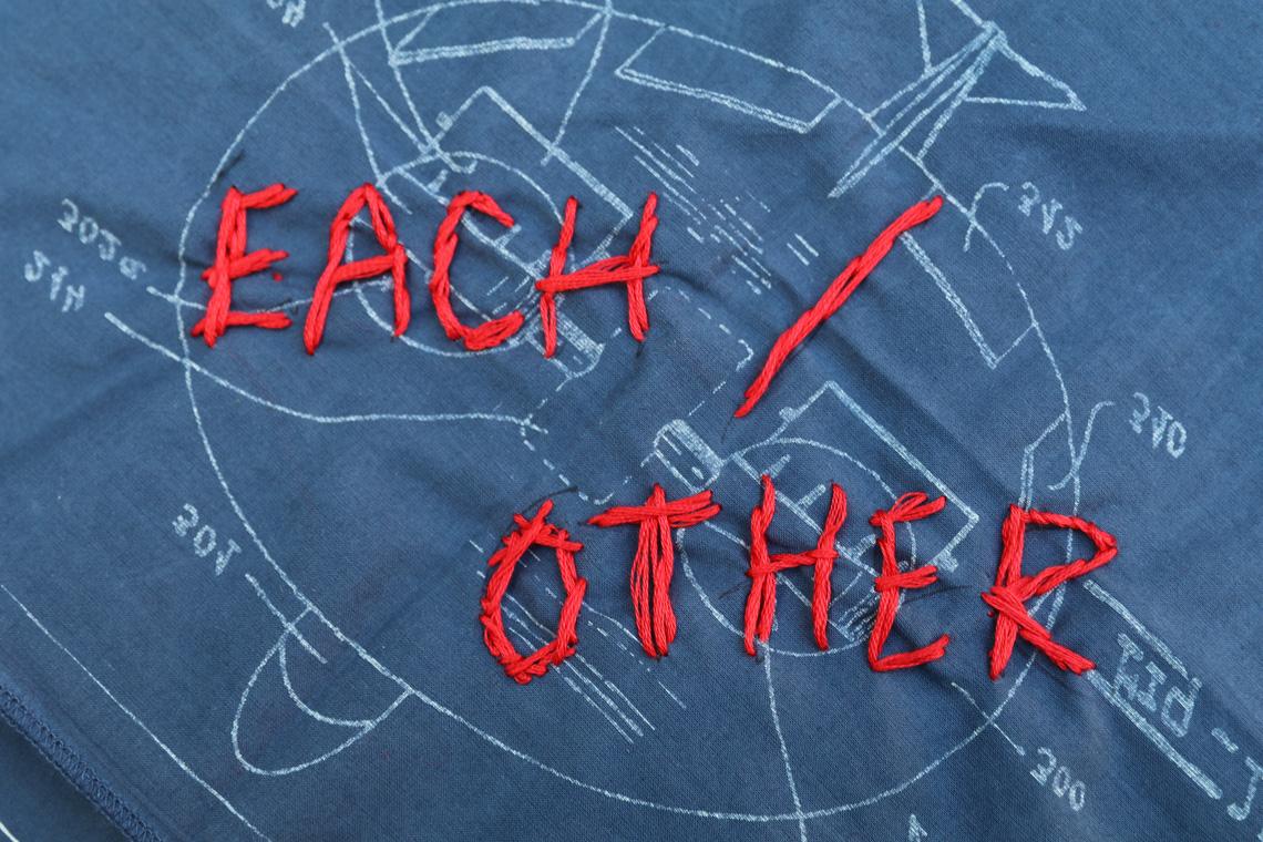 The words "Each Other" embroidered on a bandana