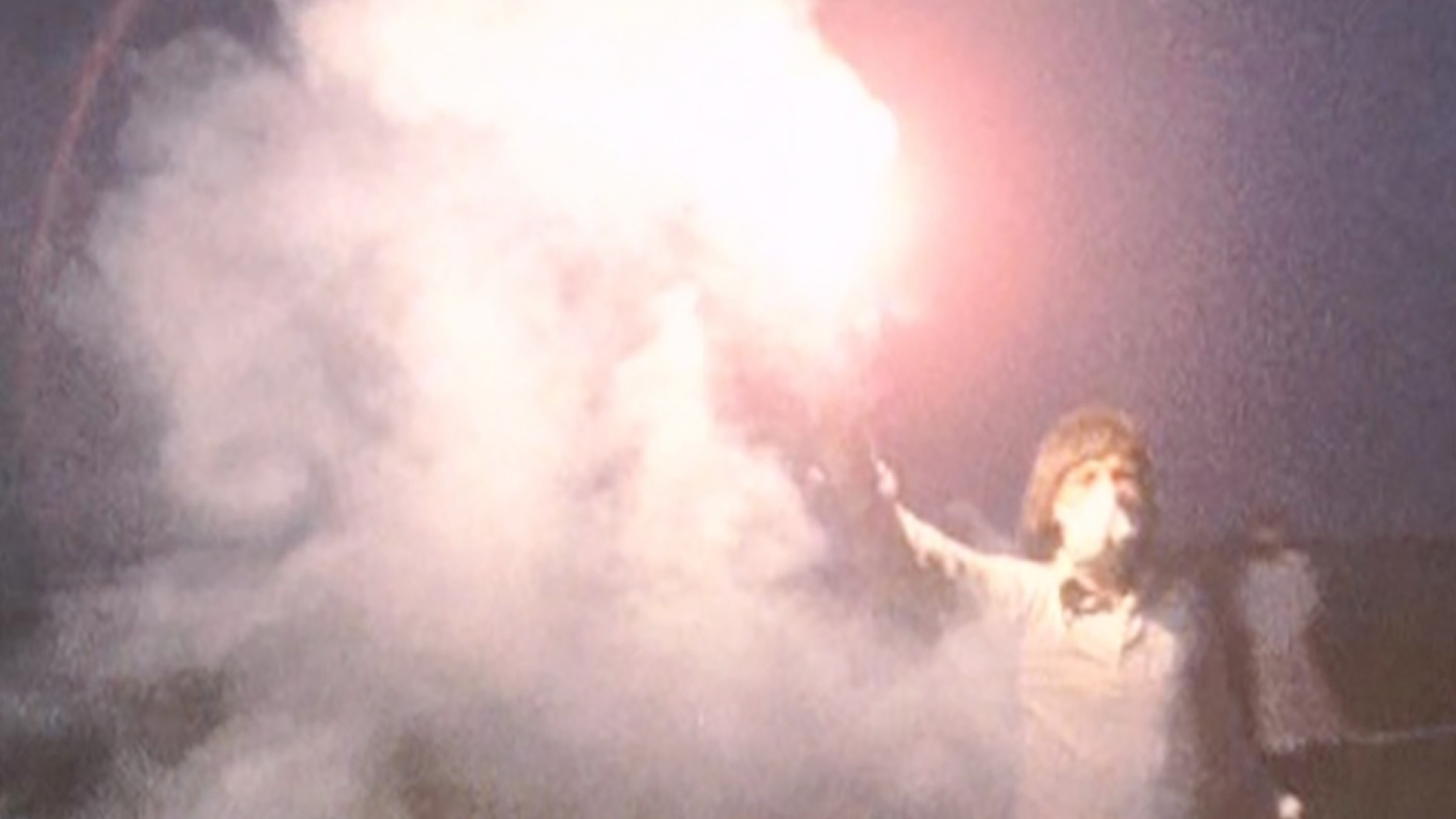 film still of a person wearing white holding a torn in the air