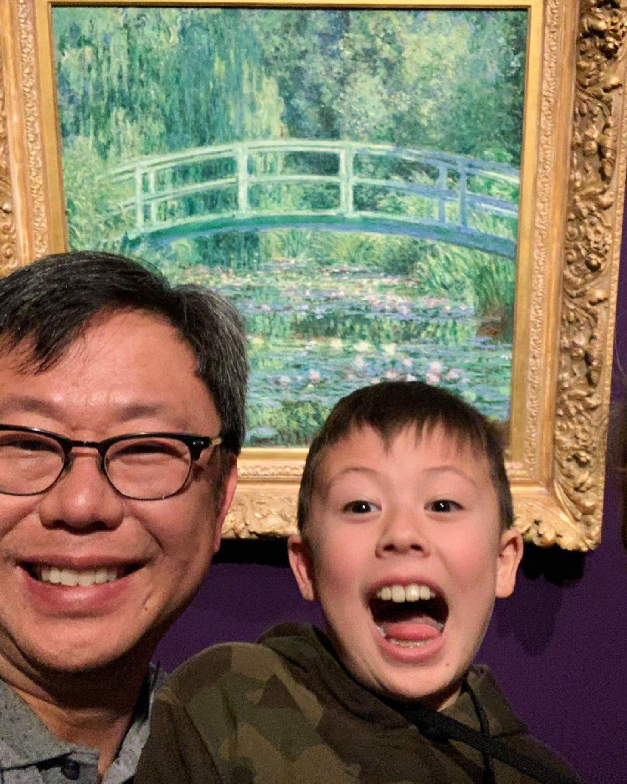 A father and son visitor smile in front of The Japanese Bridge by Claude Monet