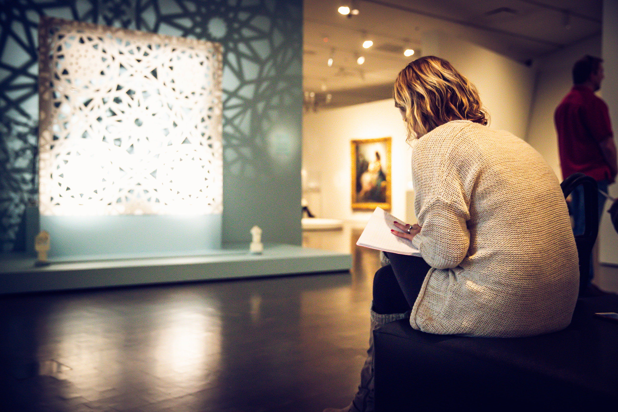 Woman writing in her notebook in front of an artwork