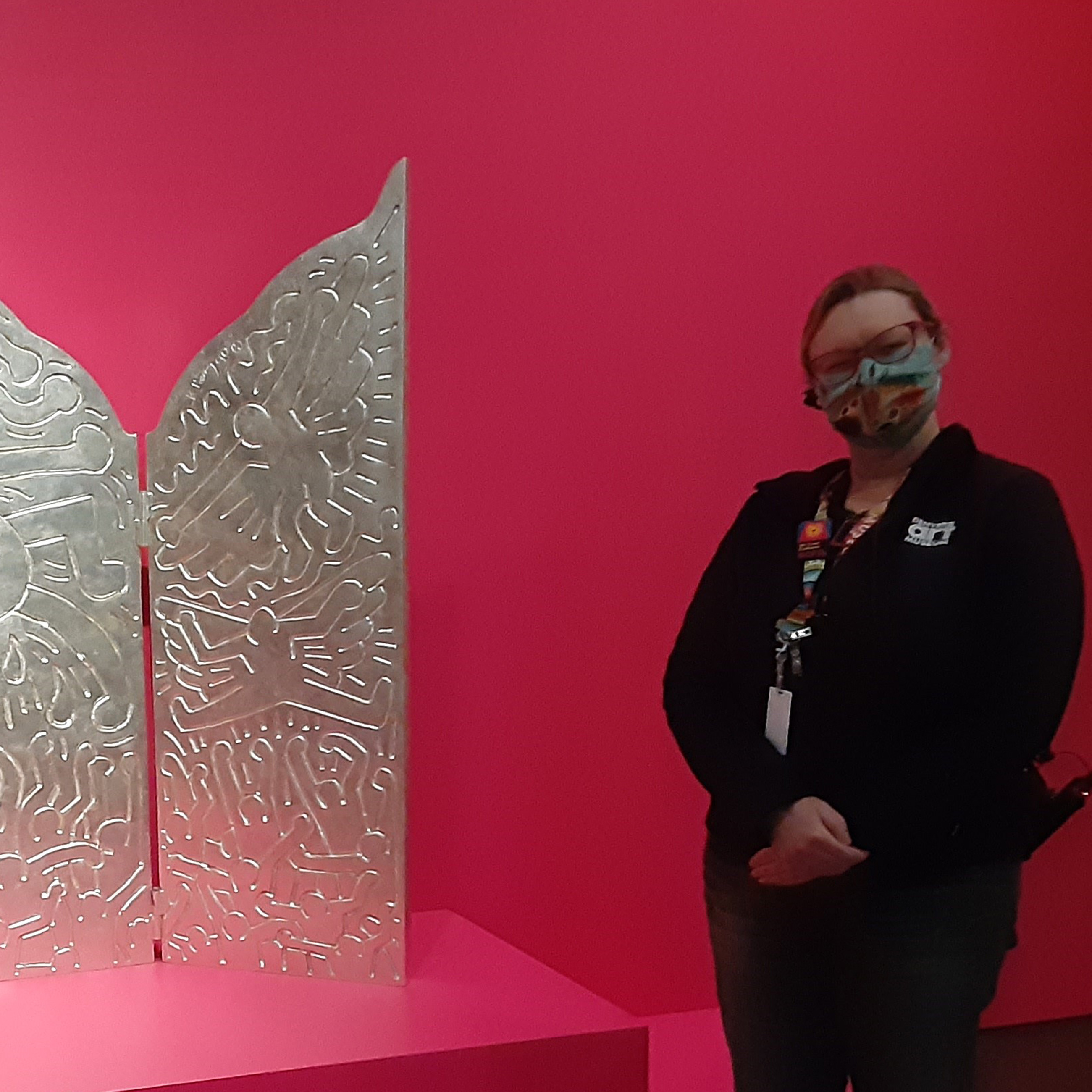 Rebecca Rowley next to a silver-colored sculpture in one of the art galleries