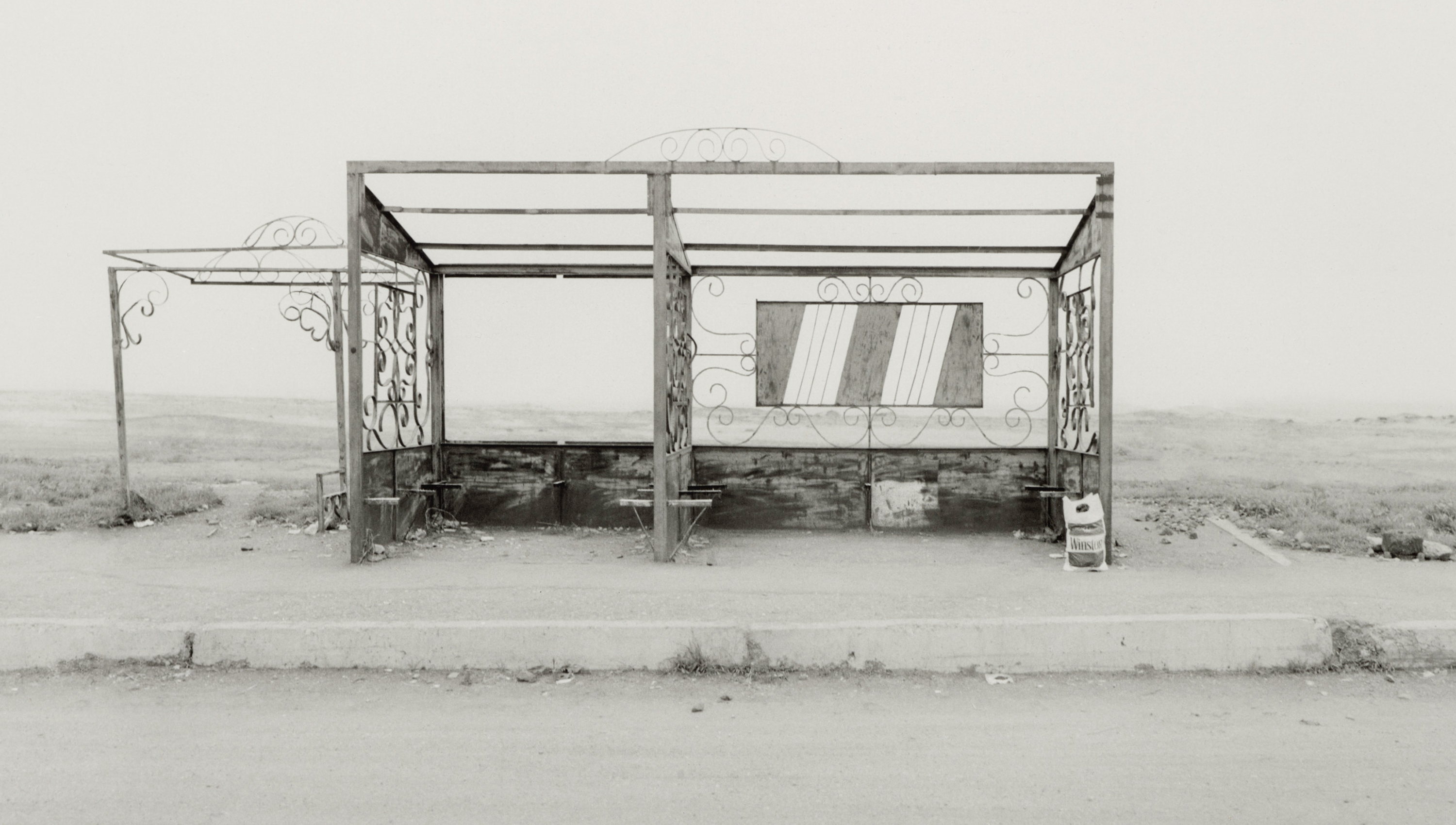 black and white photo of a bus stop in a remote area