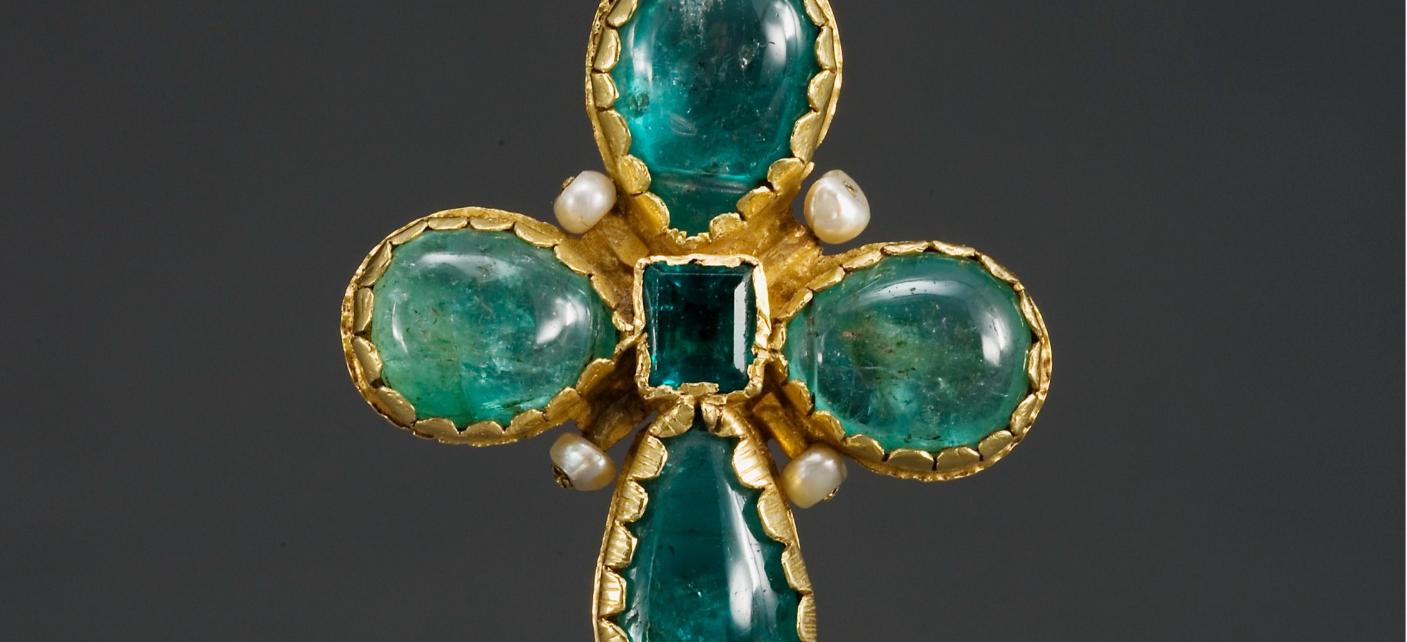 A gold cross adorned with emeralds and pearls.