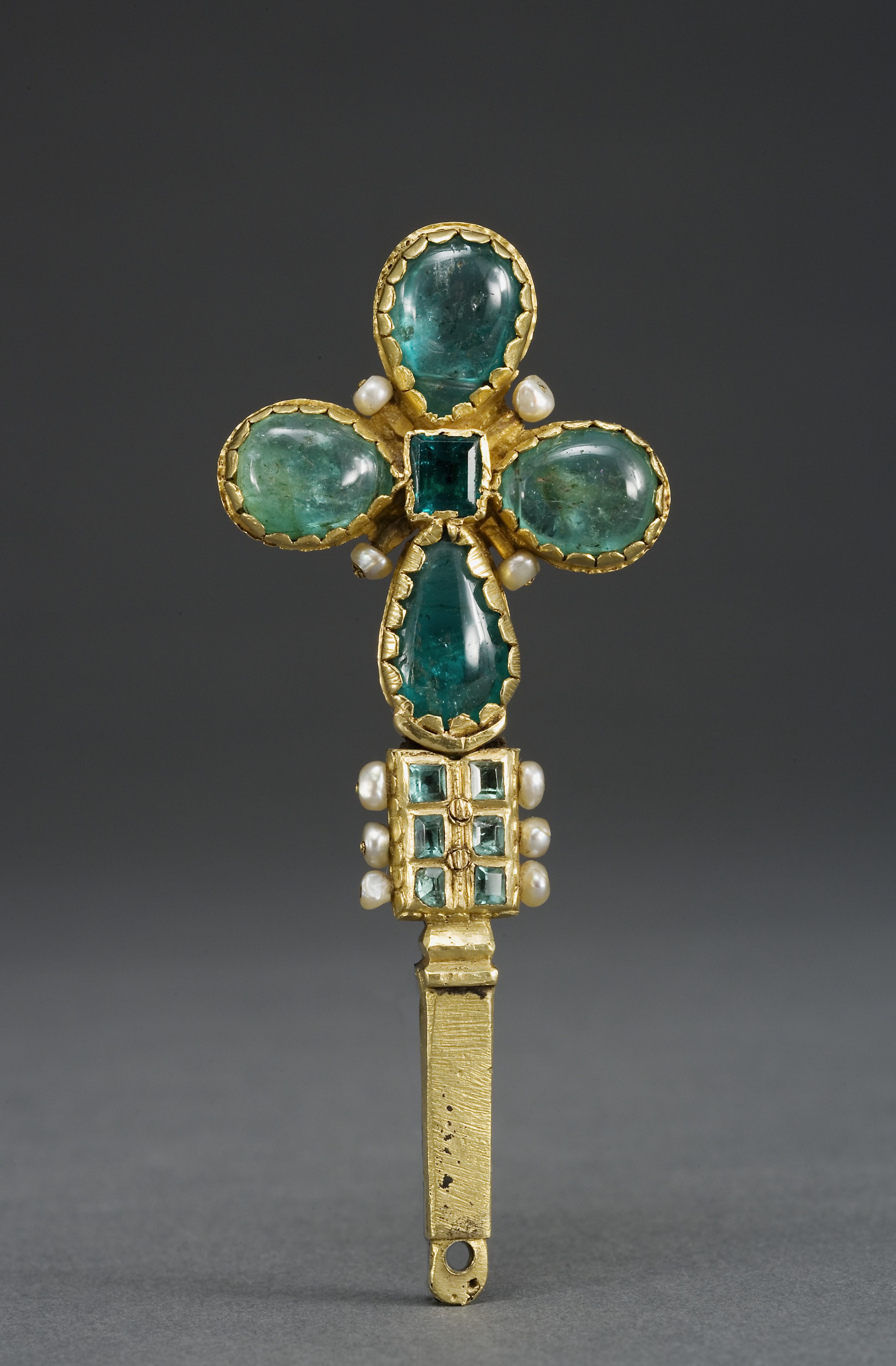 A gold cross adorned with emeralds and pearls.