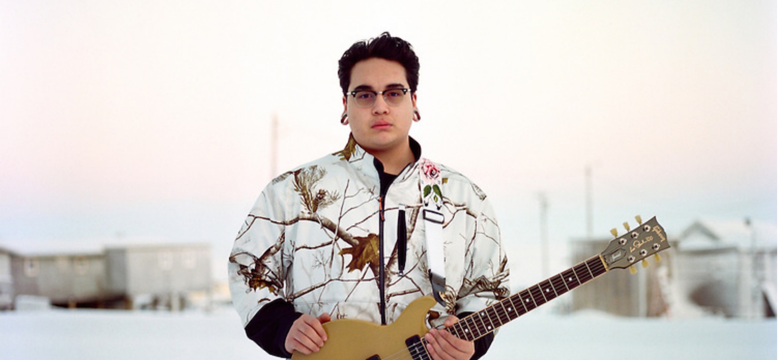 A photograph of Jonas Mackenzie holding a guitar taken by Brian Adams.