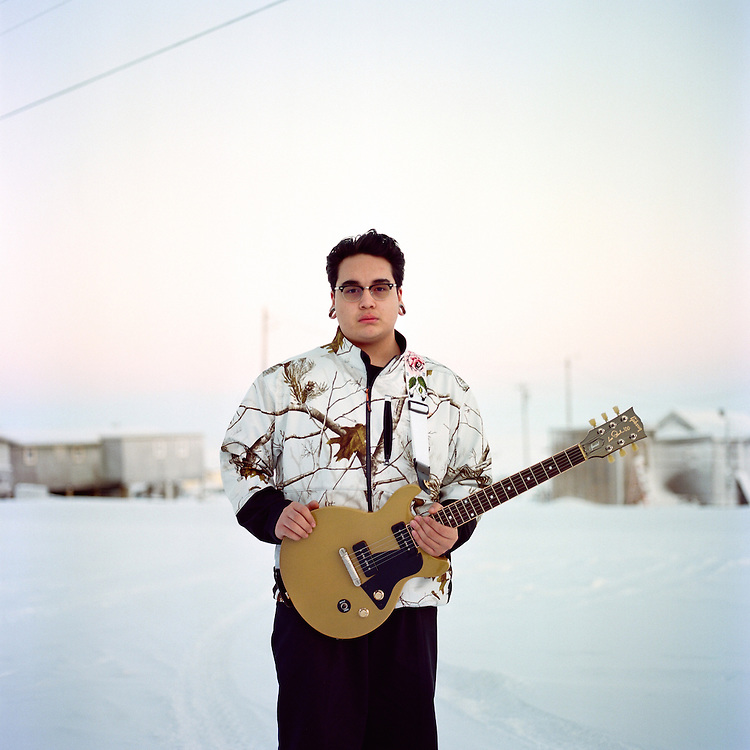 A photograph of Jonas Mackenzie holding a guitar taken by Brian Adams.