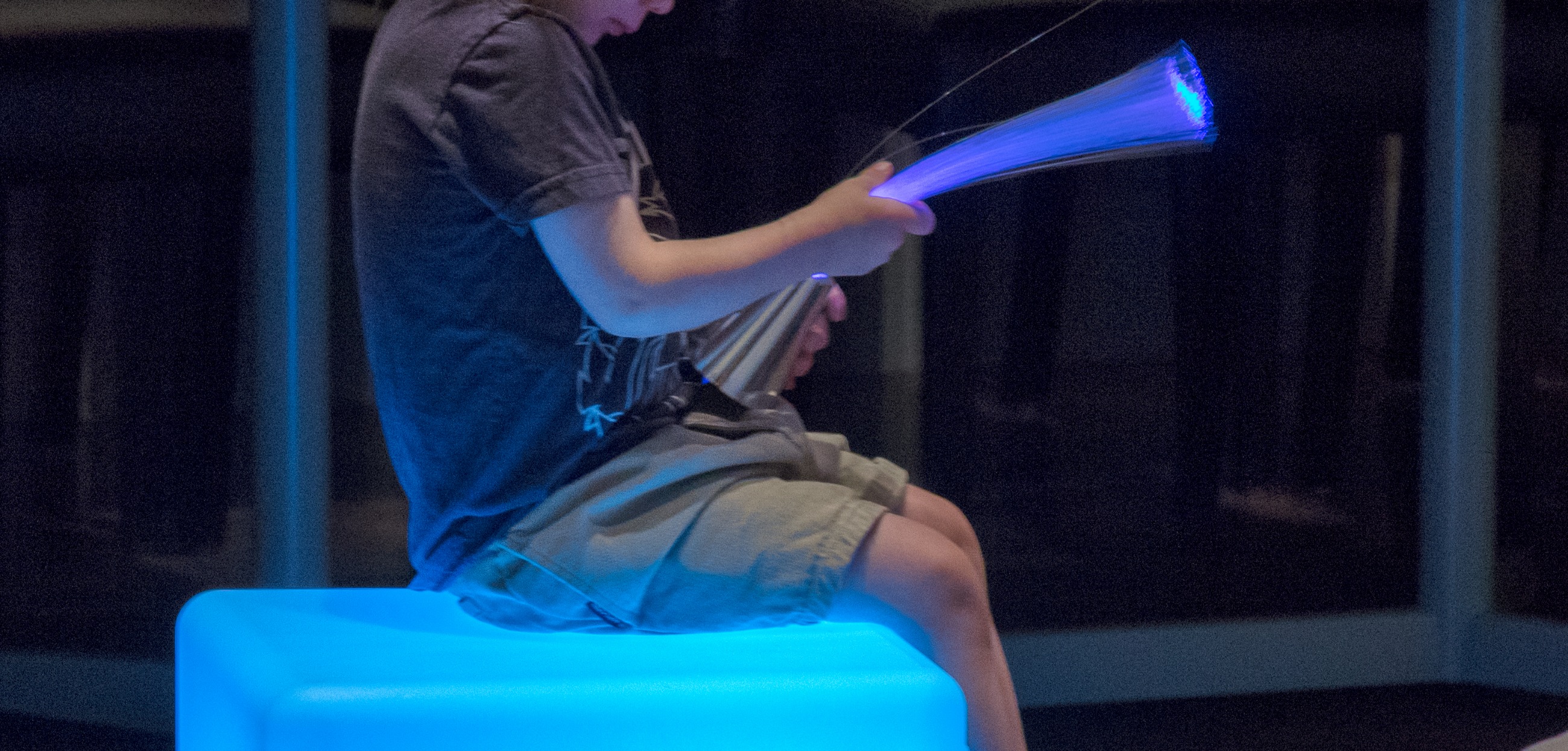 Child at the Denver Art Museum's Low Sensory Mornings event playing with a fiber optic toy.