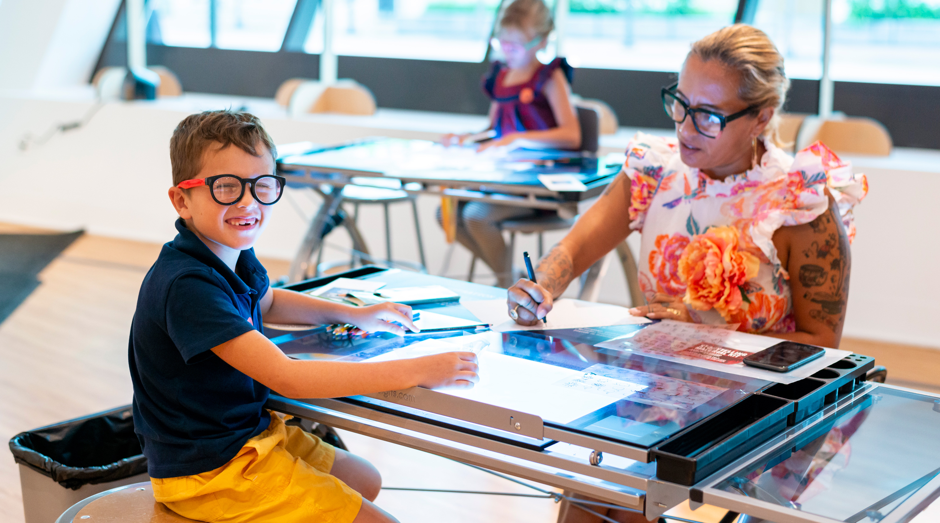 Young boy and parent creating art at a table in the museum.