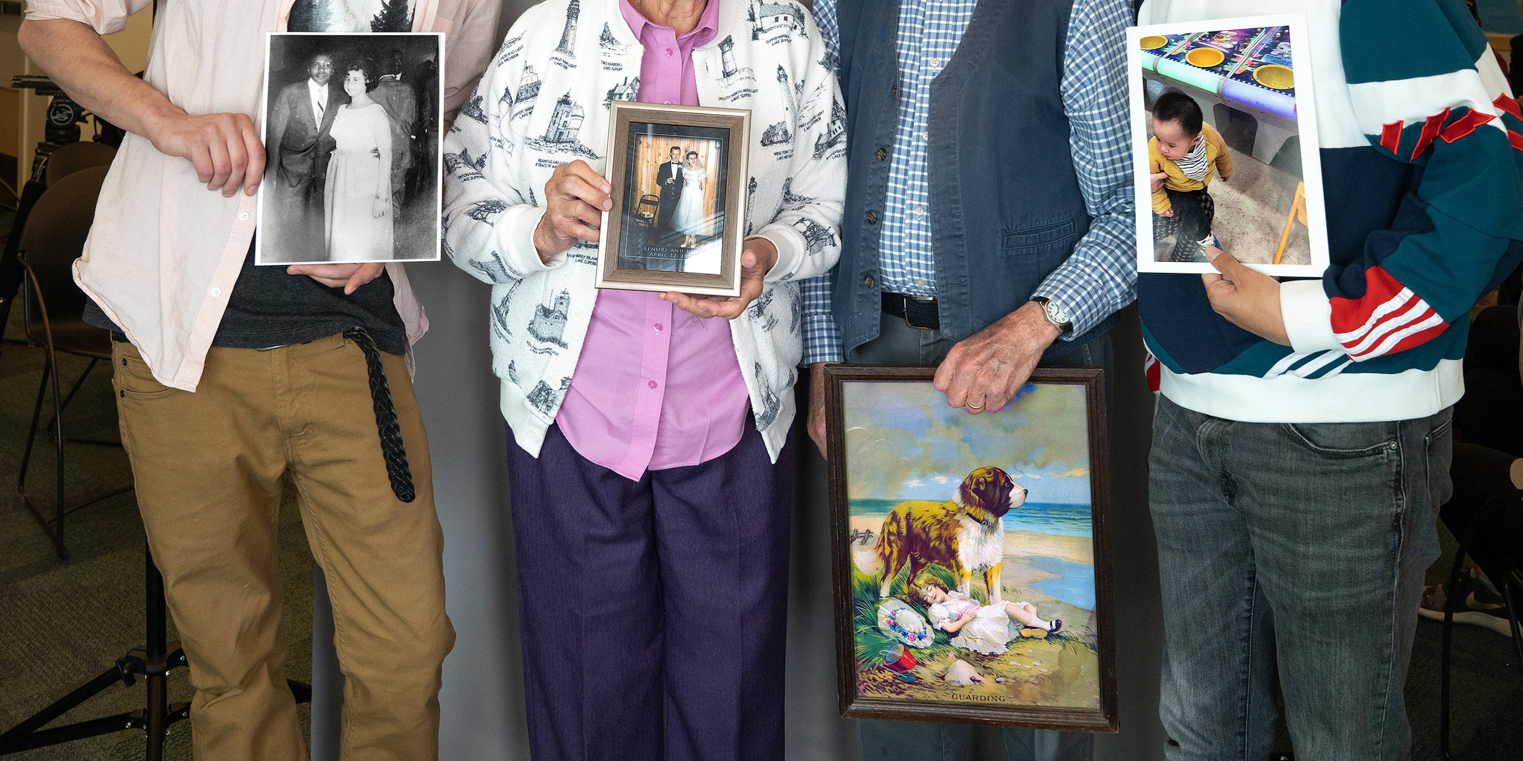 4 people only shown from the neck down holding photos