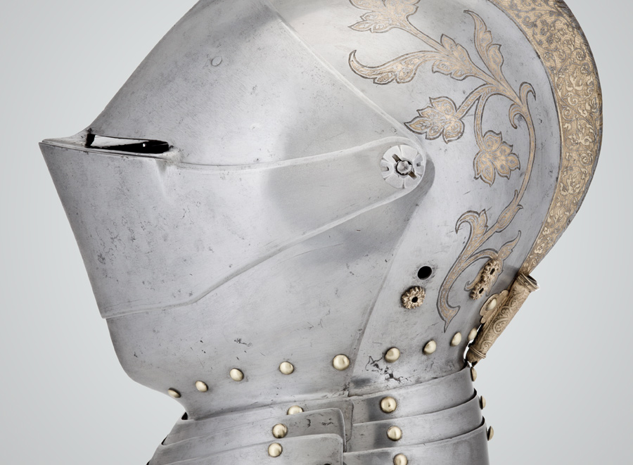 Profile view of a steel and brass tournament helmet that covers entire face and head