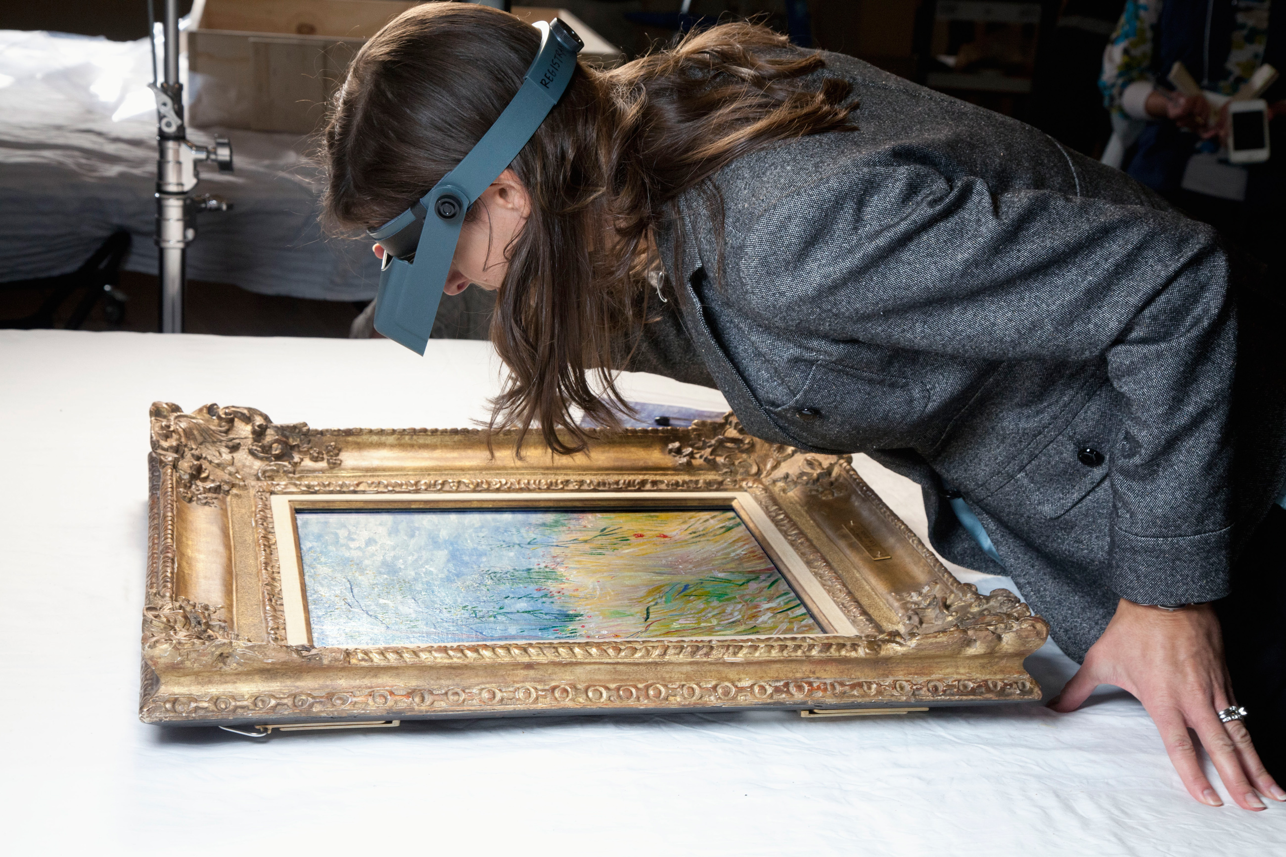 Woman leaning in to examine a painting with goggles on