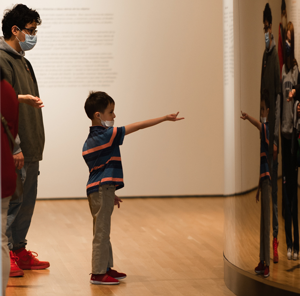 Child pointing at themselves in a reflective mirror