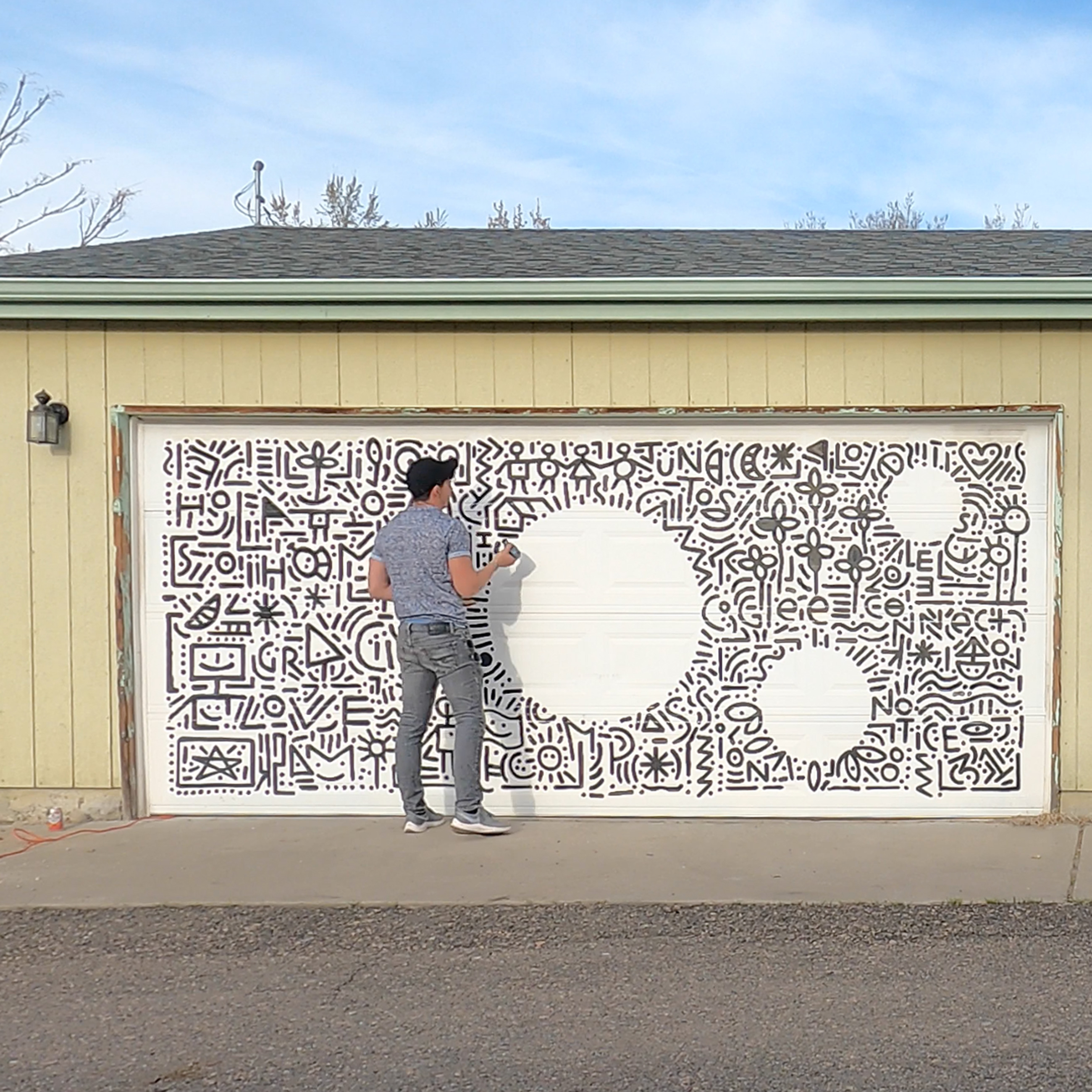 Charlo Garcia Walterbach painting a mural on a garage door
