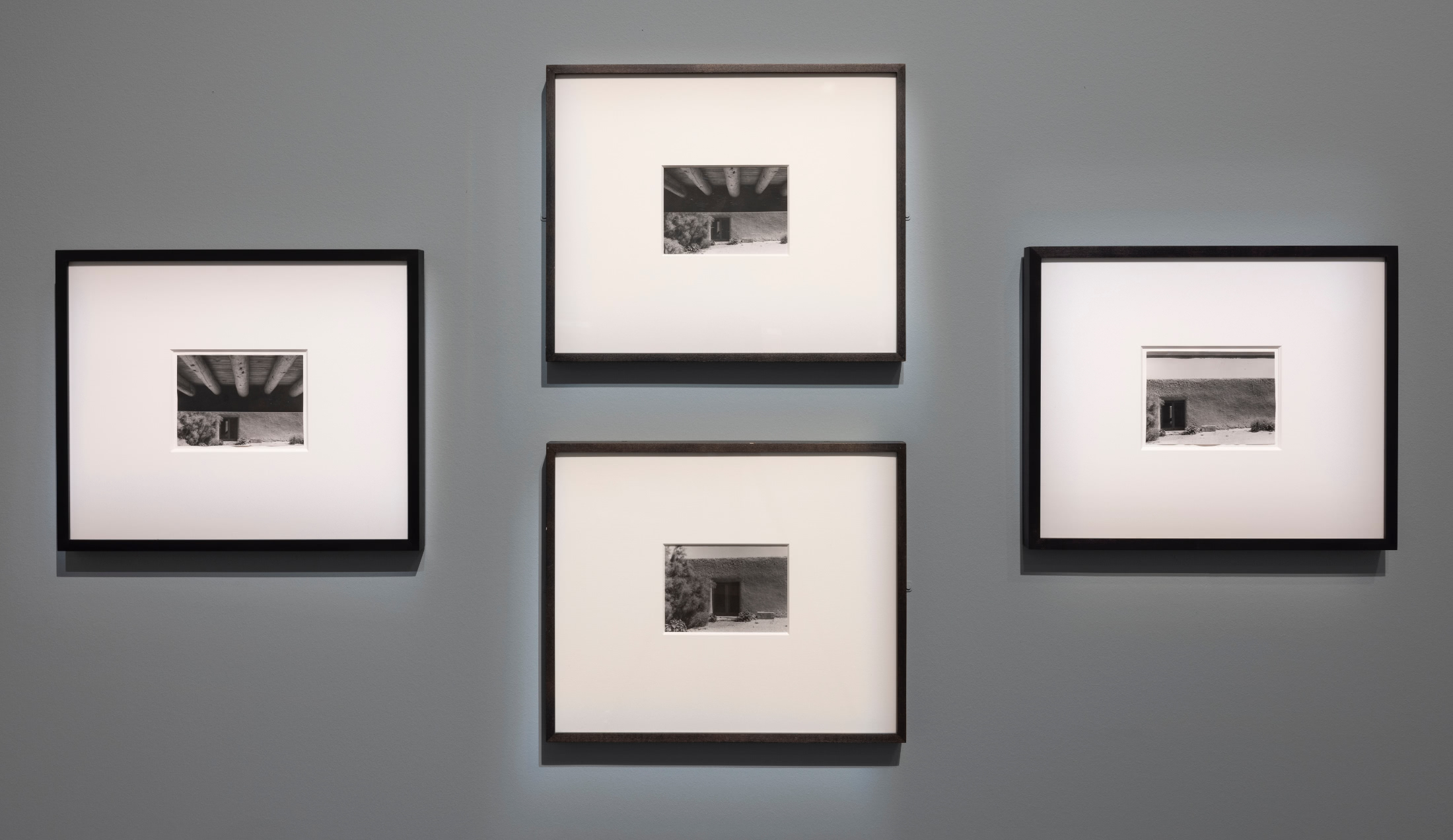A set of four black and white photographs of the dark doorway of an adobe building. The photographs are taken from various distances and angles of the same doorway.