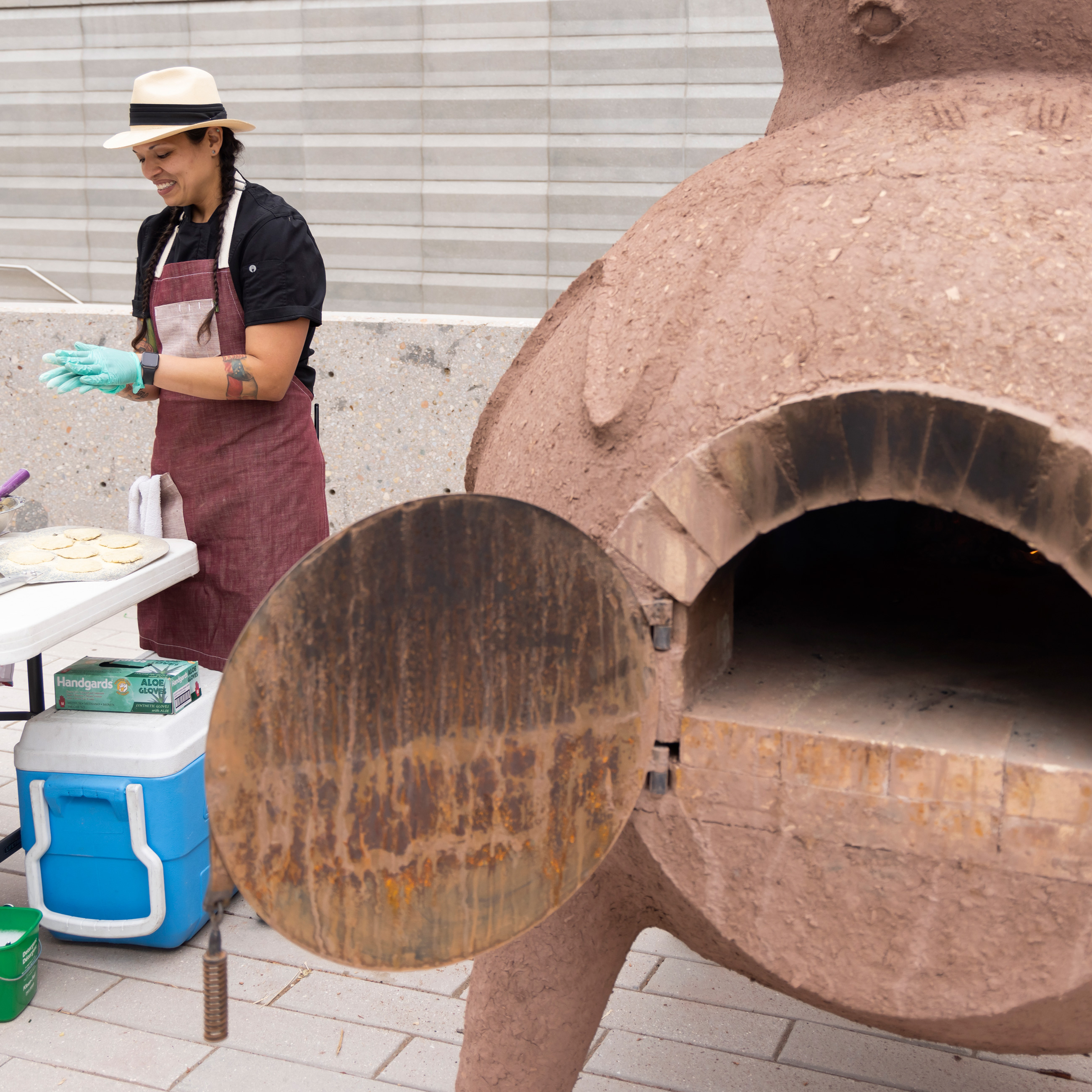 Andrea Murdoch making flatbread next to the large ceramic oven outside the Denver Art Museum