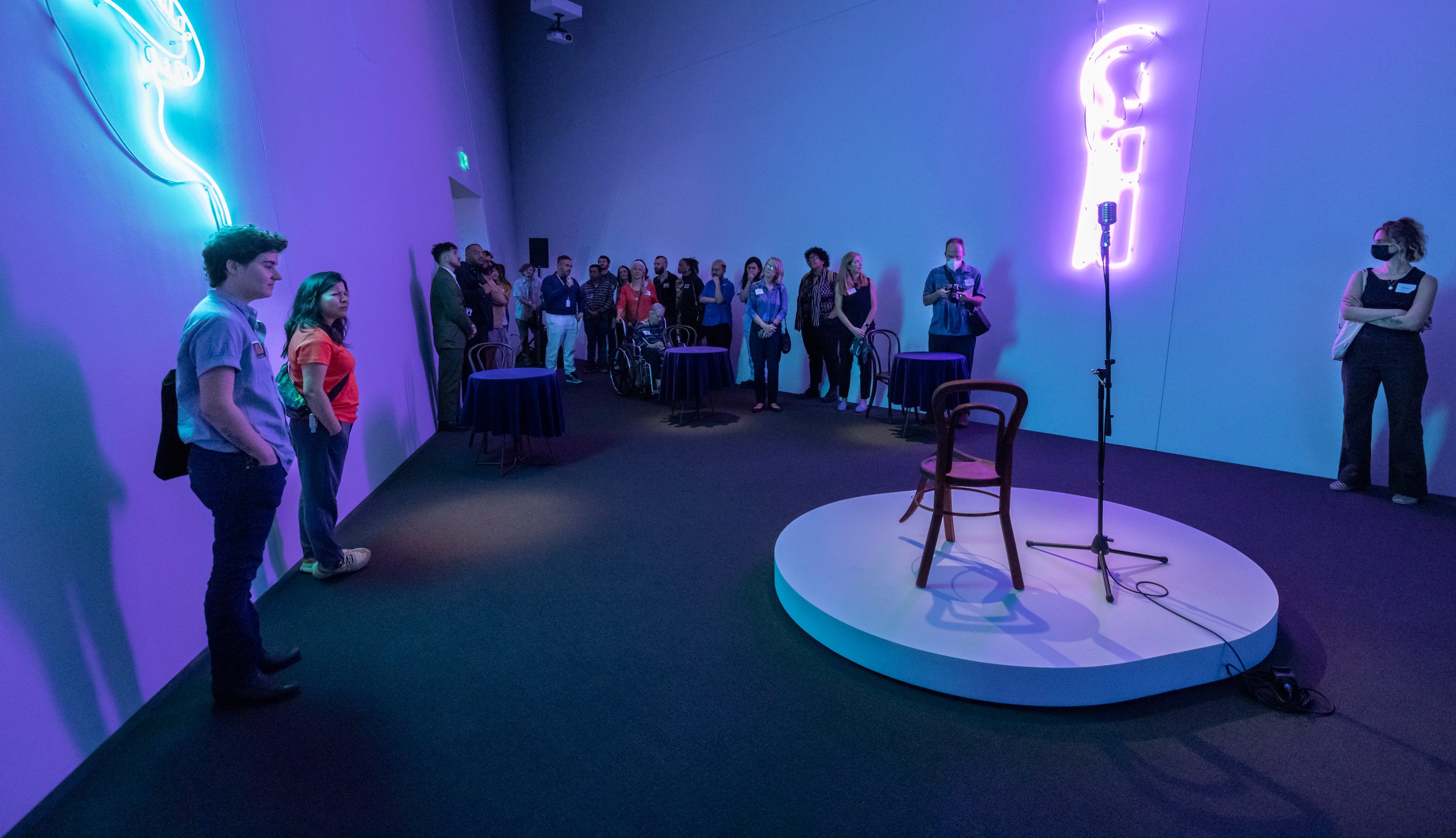 People standing in a neon backlit room with a small stage in the center