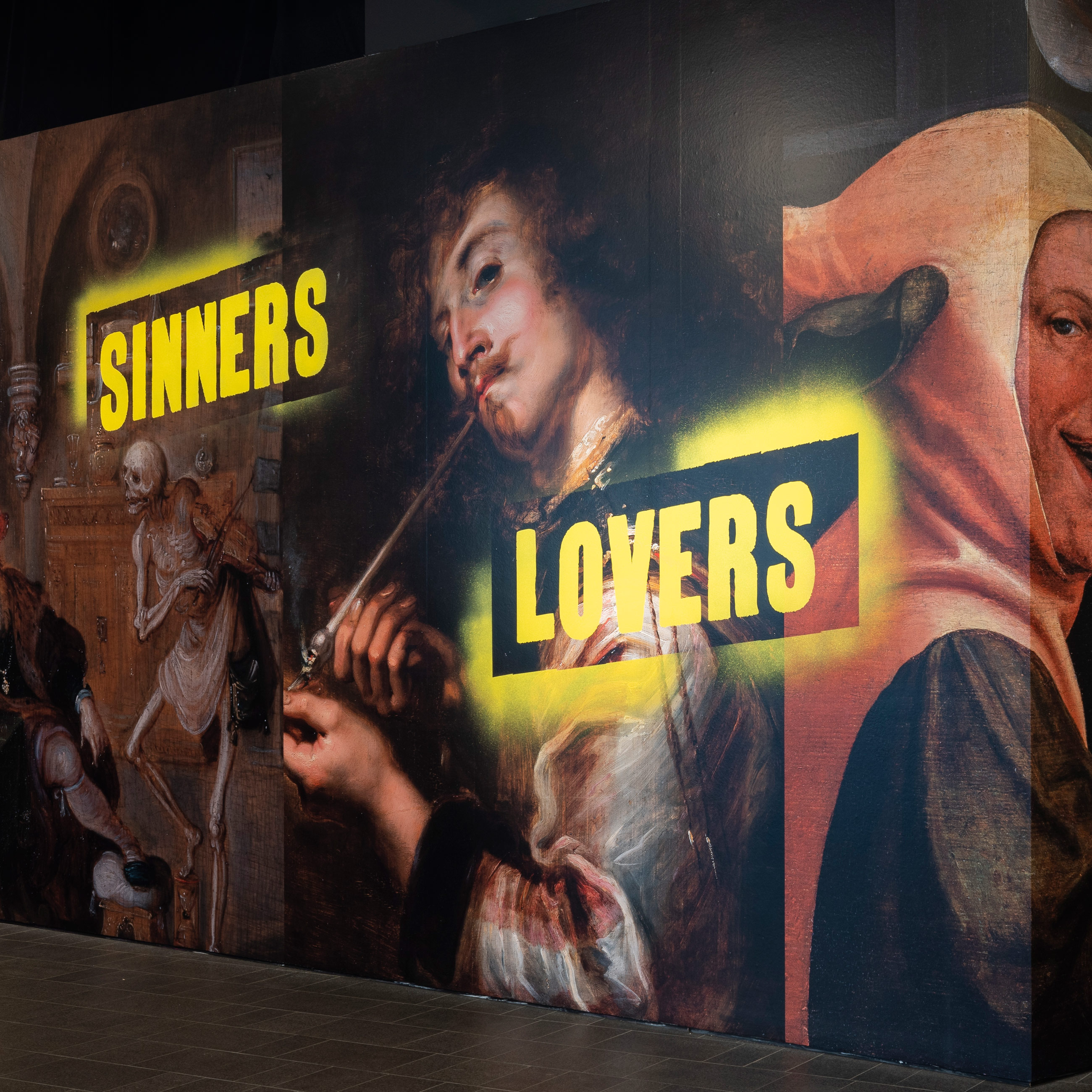 part of the exhibition title wall showing the words sinners and lovers with portraits in the exhibition