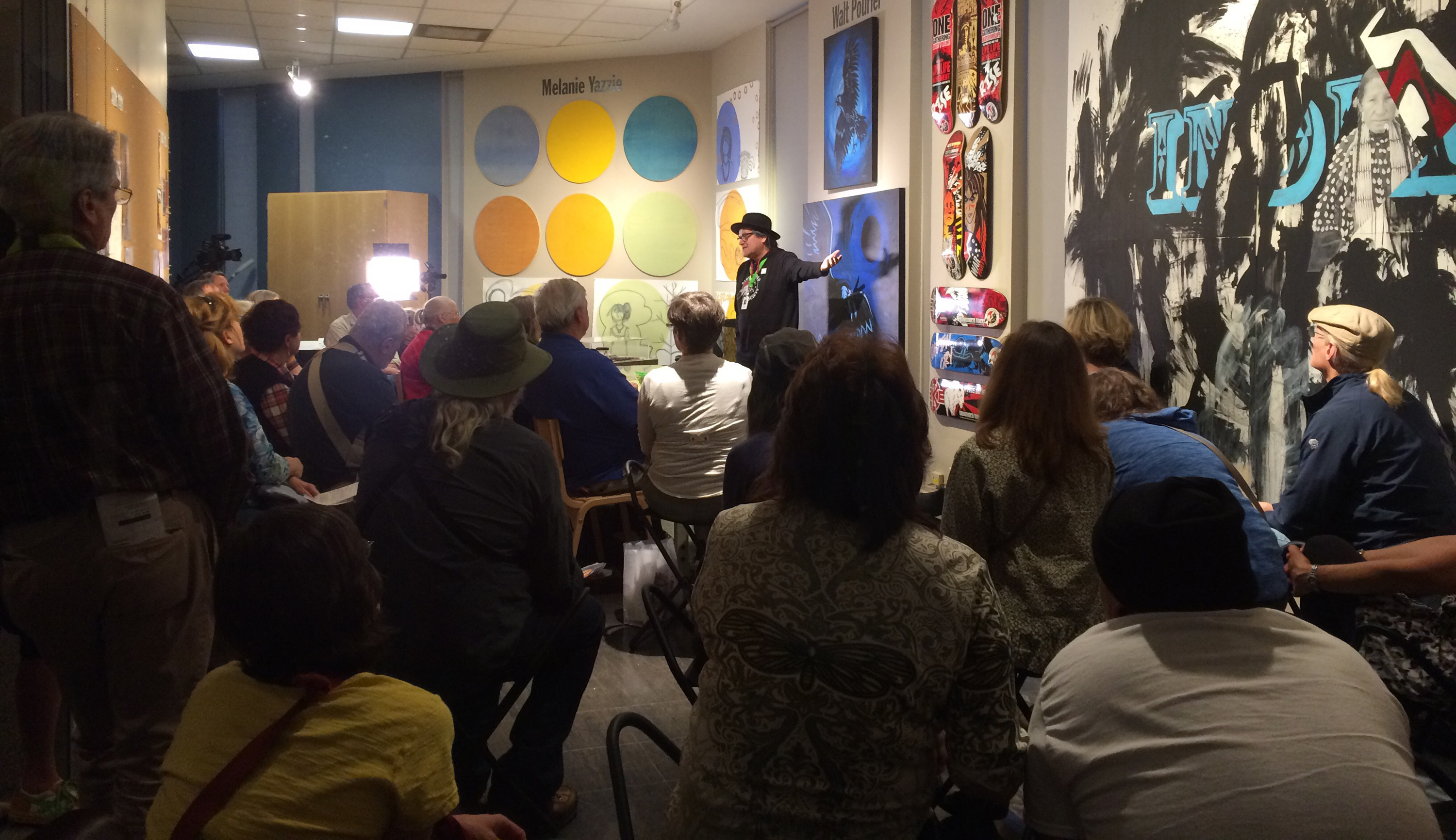 Artist Walt Pourier giving a talk to a crowd of people inside the artist studio