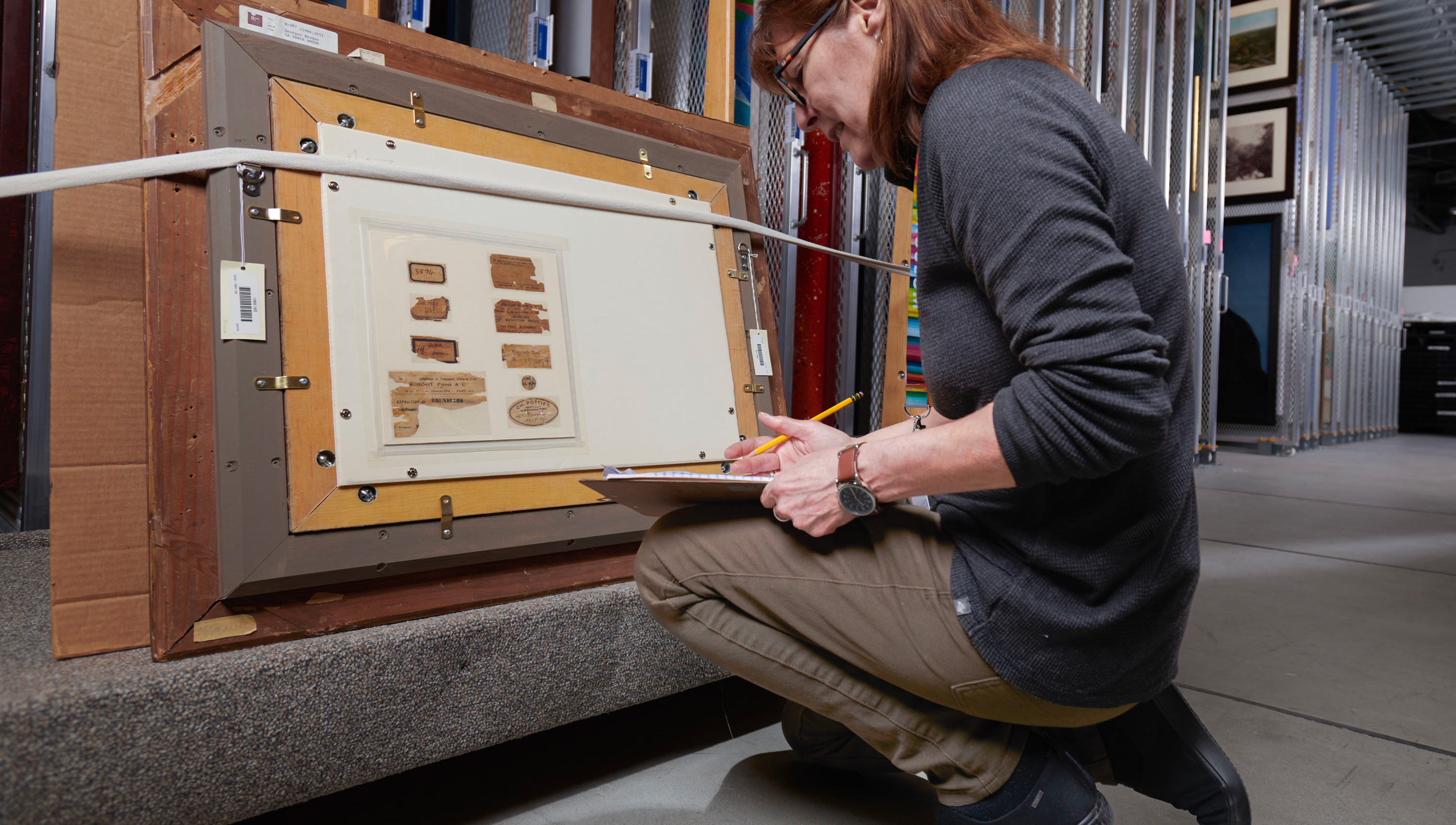 Provenance researcher Lori Iliff looking at the back of an artwork in storage