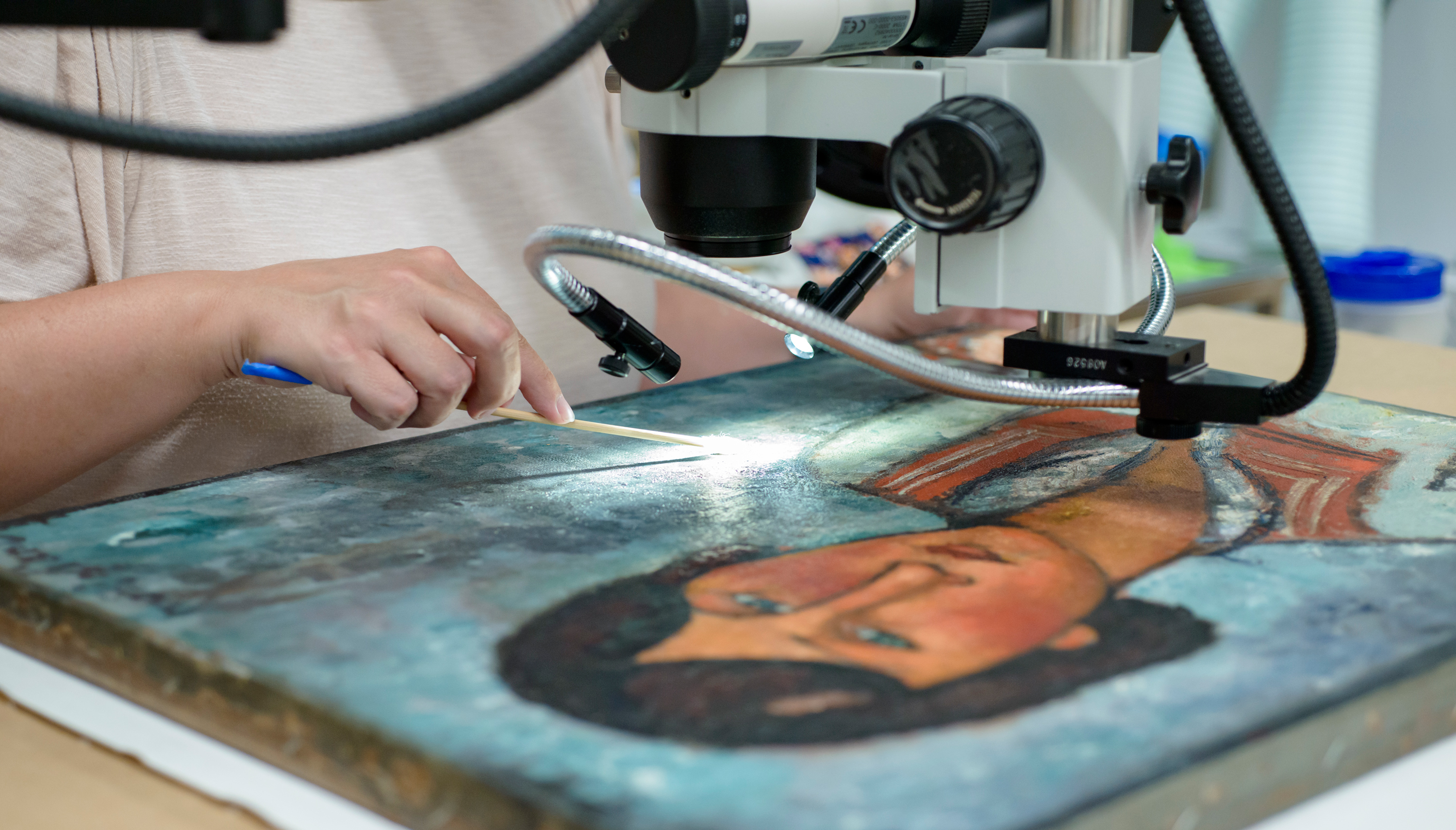 Woman working on restoring a painting in the conservation lab