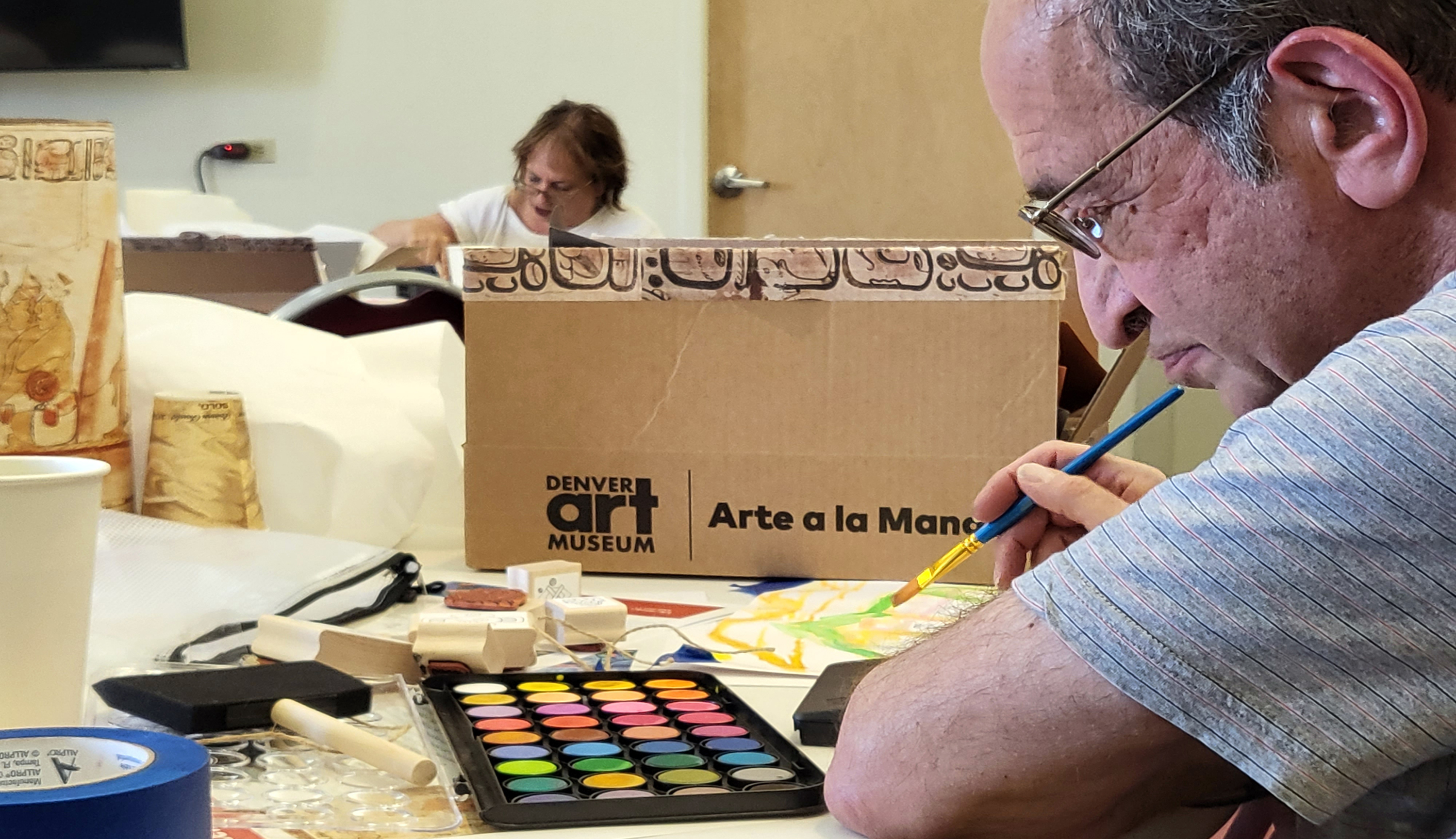 Older gentleman working with paints to create an art at hand box