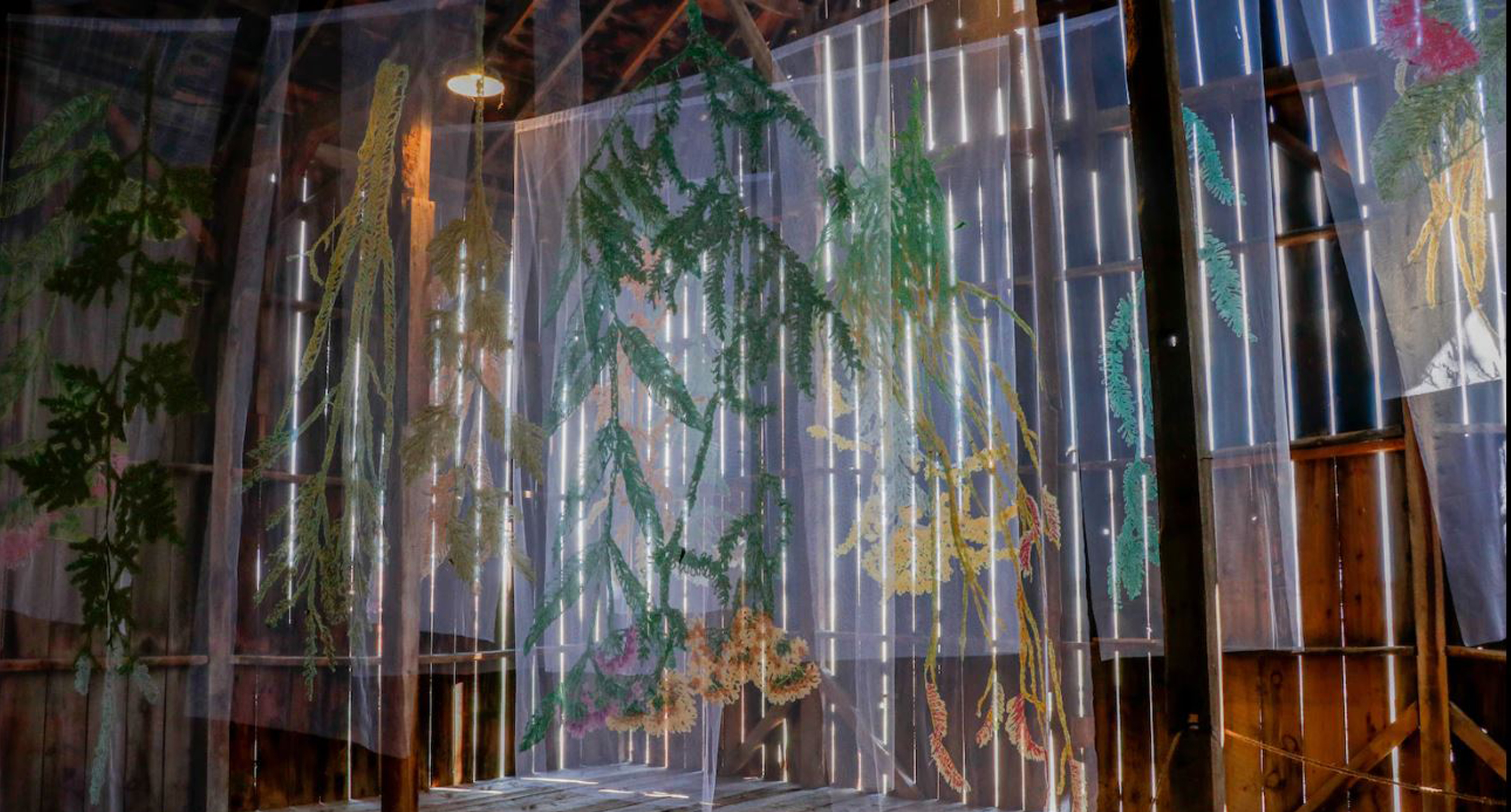 Site-specific installation with hanging leaves in a wooden shack