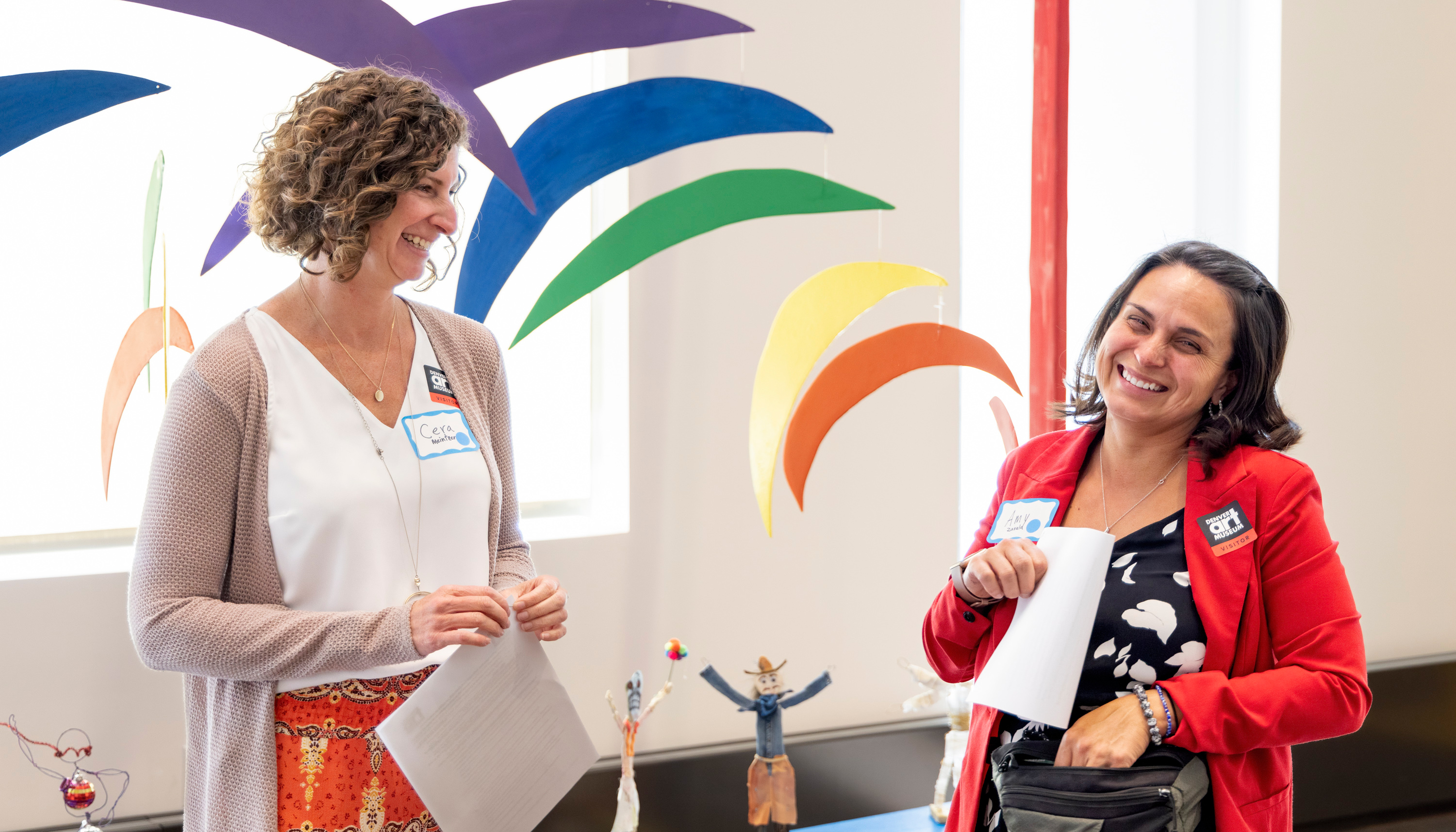 Two women smiling and laughing in a museum conference room