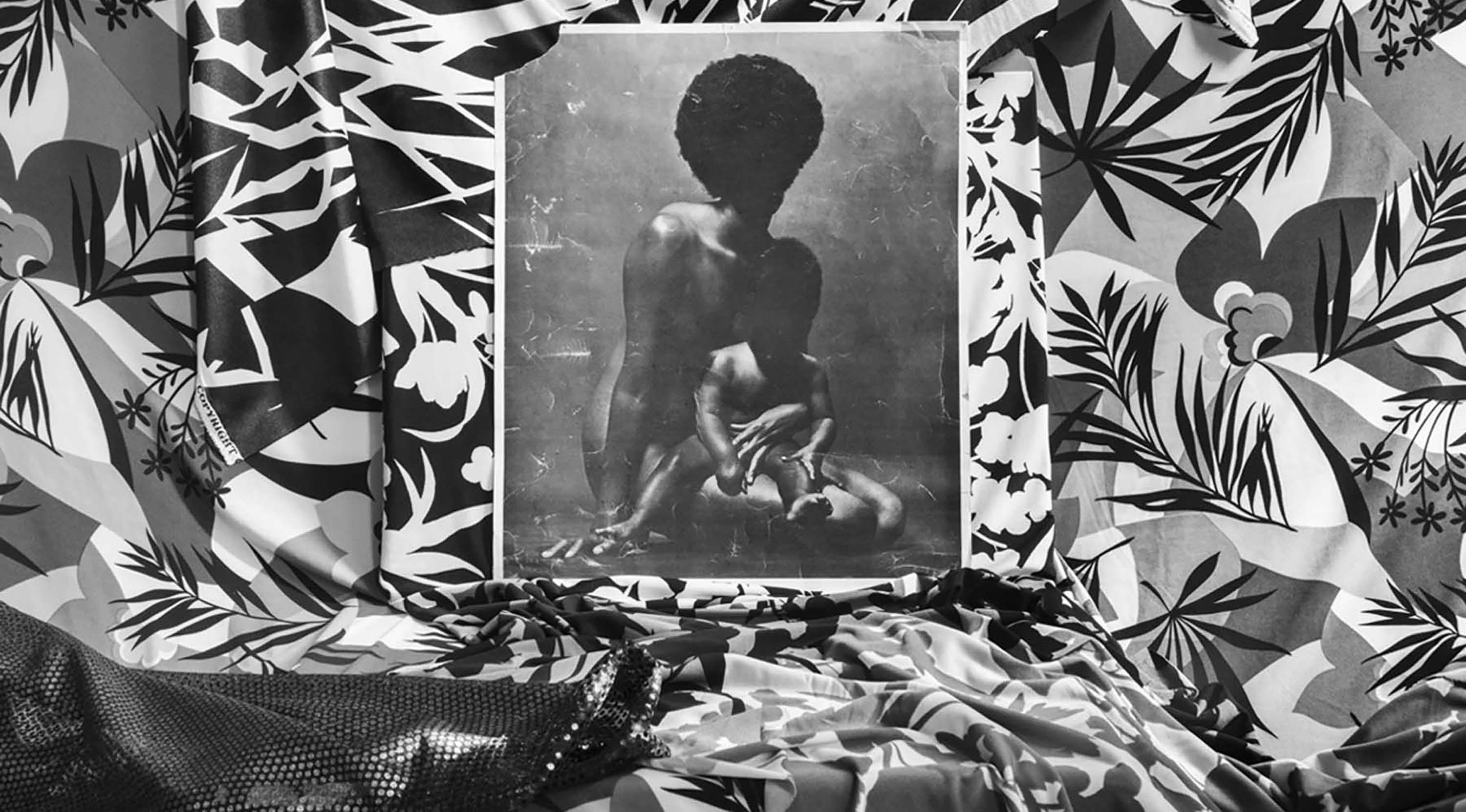 Photograph of a black mother and baby surrounded by black and white patterned fabric