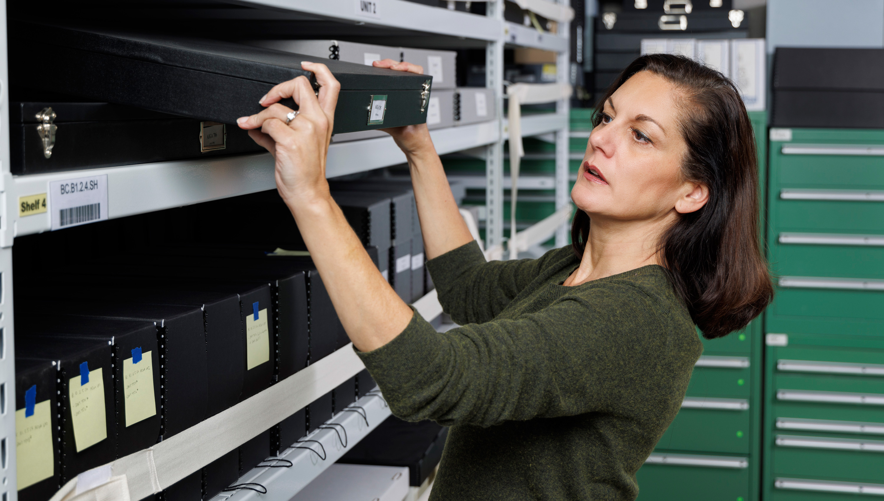 a woman picking up a black box from a shelf
