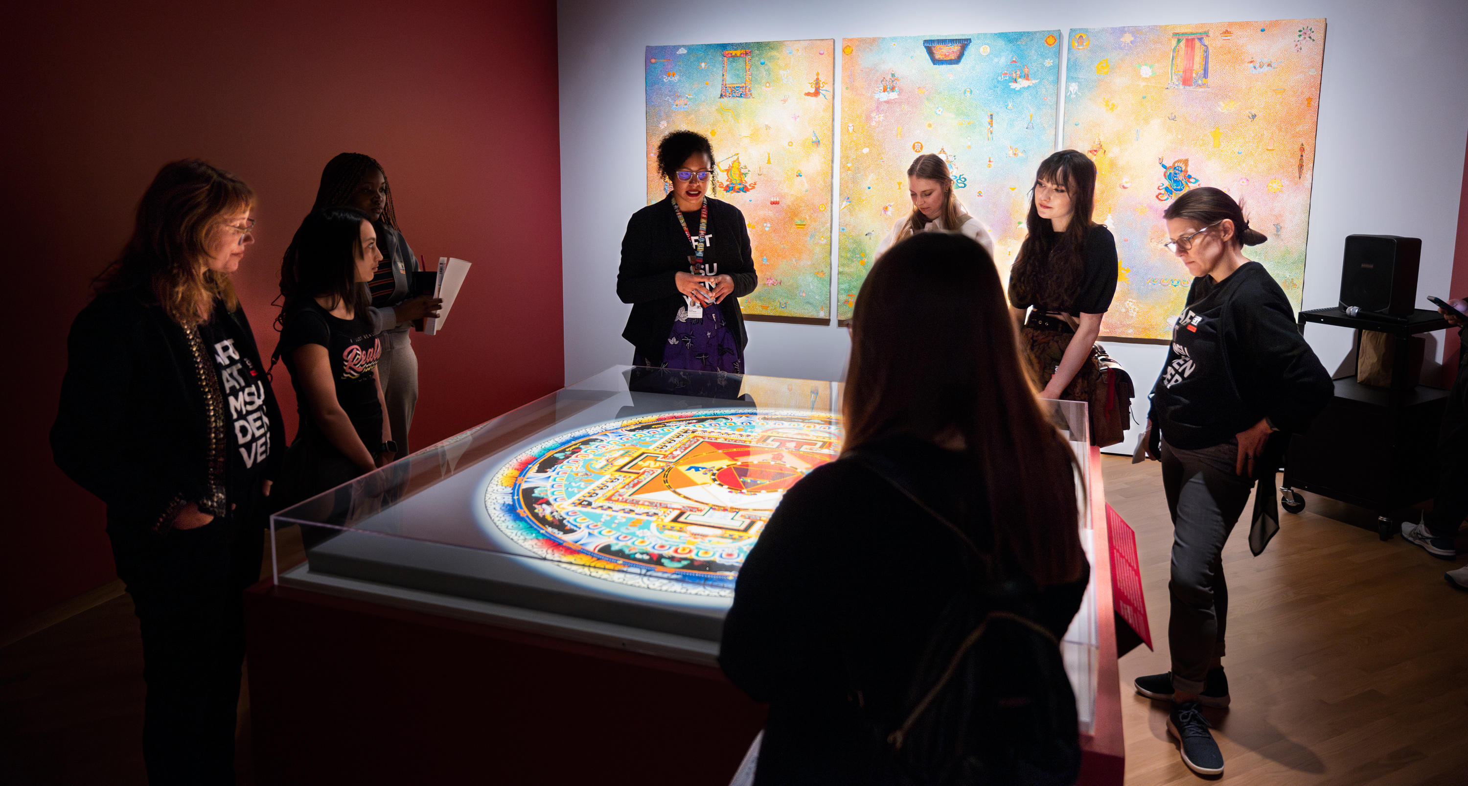 Group of visitors gathered around an encased artwork