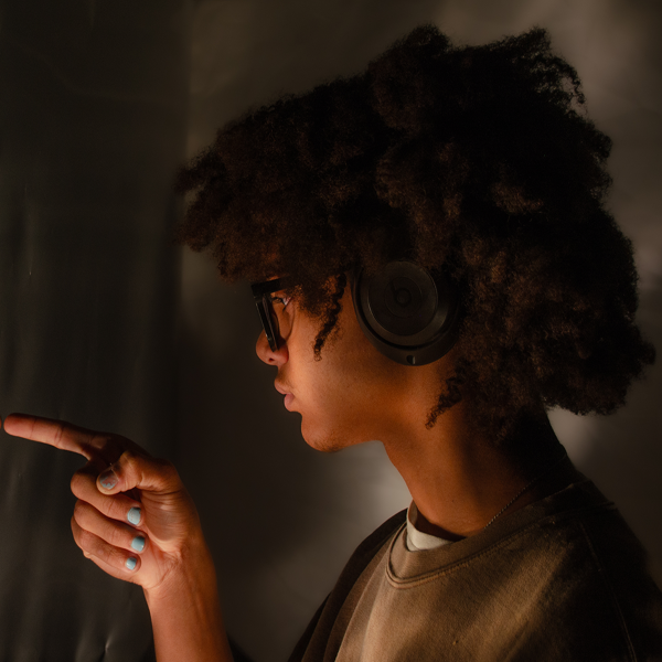 Young African American preteen with headphones on pointing at himself in a mirror