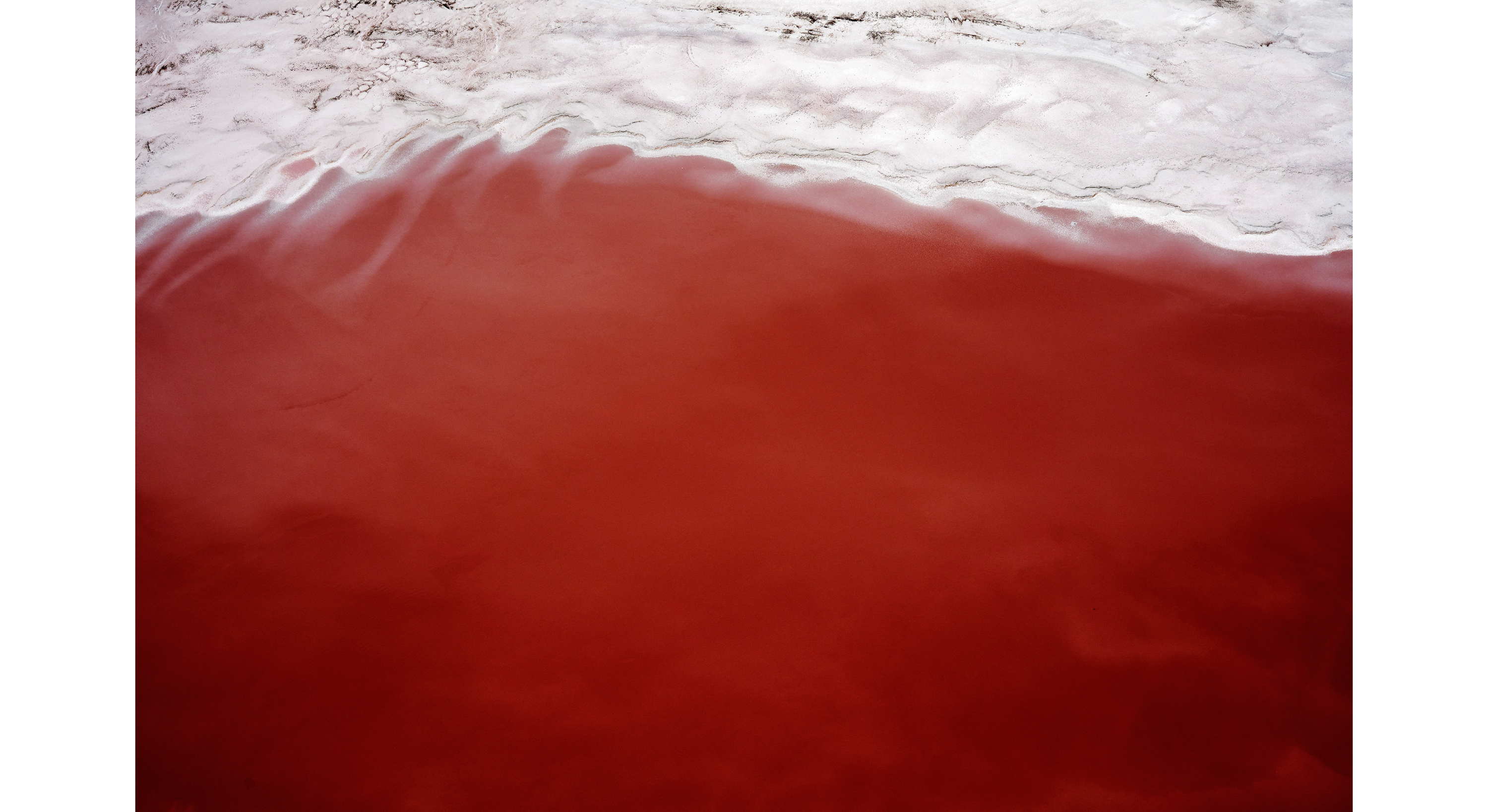 Aerial photograph of red desert sand that resembles waves in the ocean