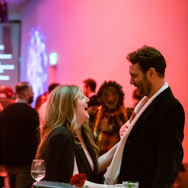 A man and woman laughing over drinks at an after hours event