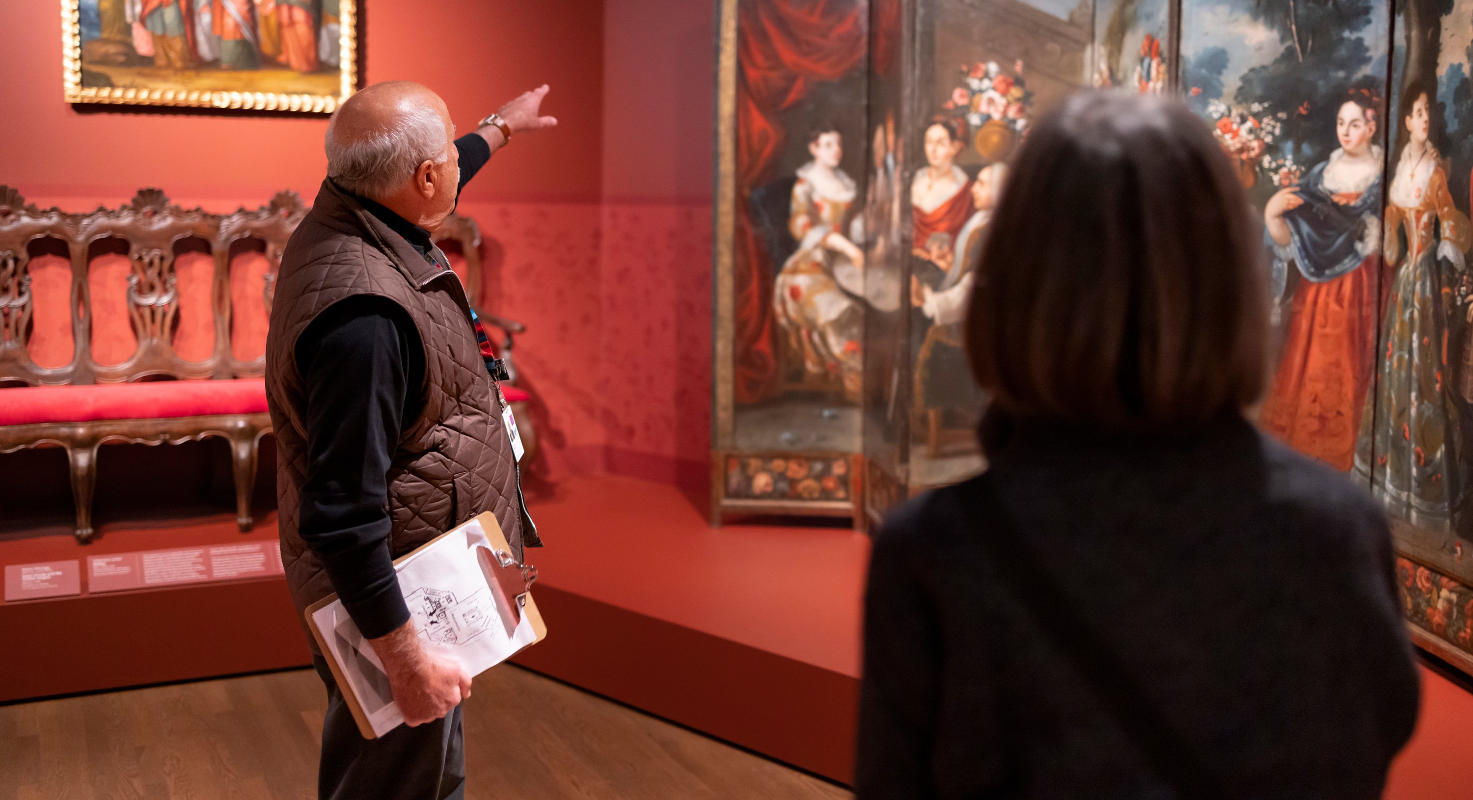 Man giving a tour in a deep red art gallery