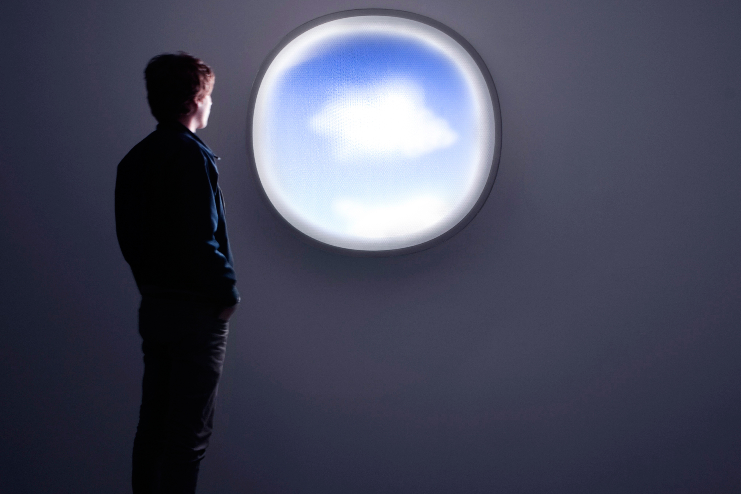 Man looking out a circular cloud-shaped window