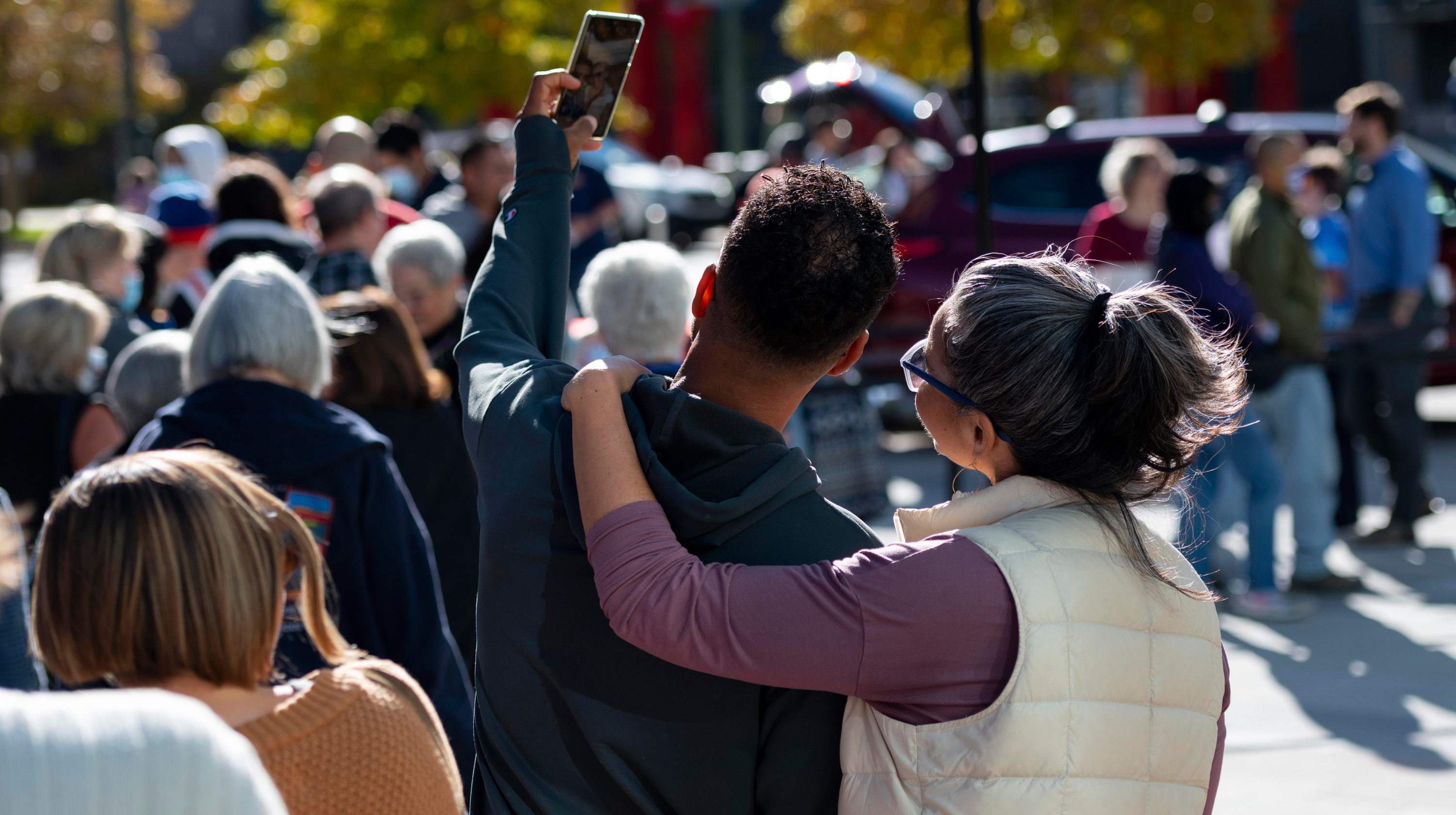 Two visitors taking a selfie together outdoors in a crowd