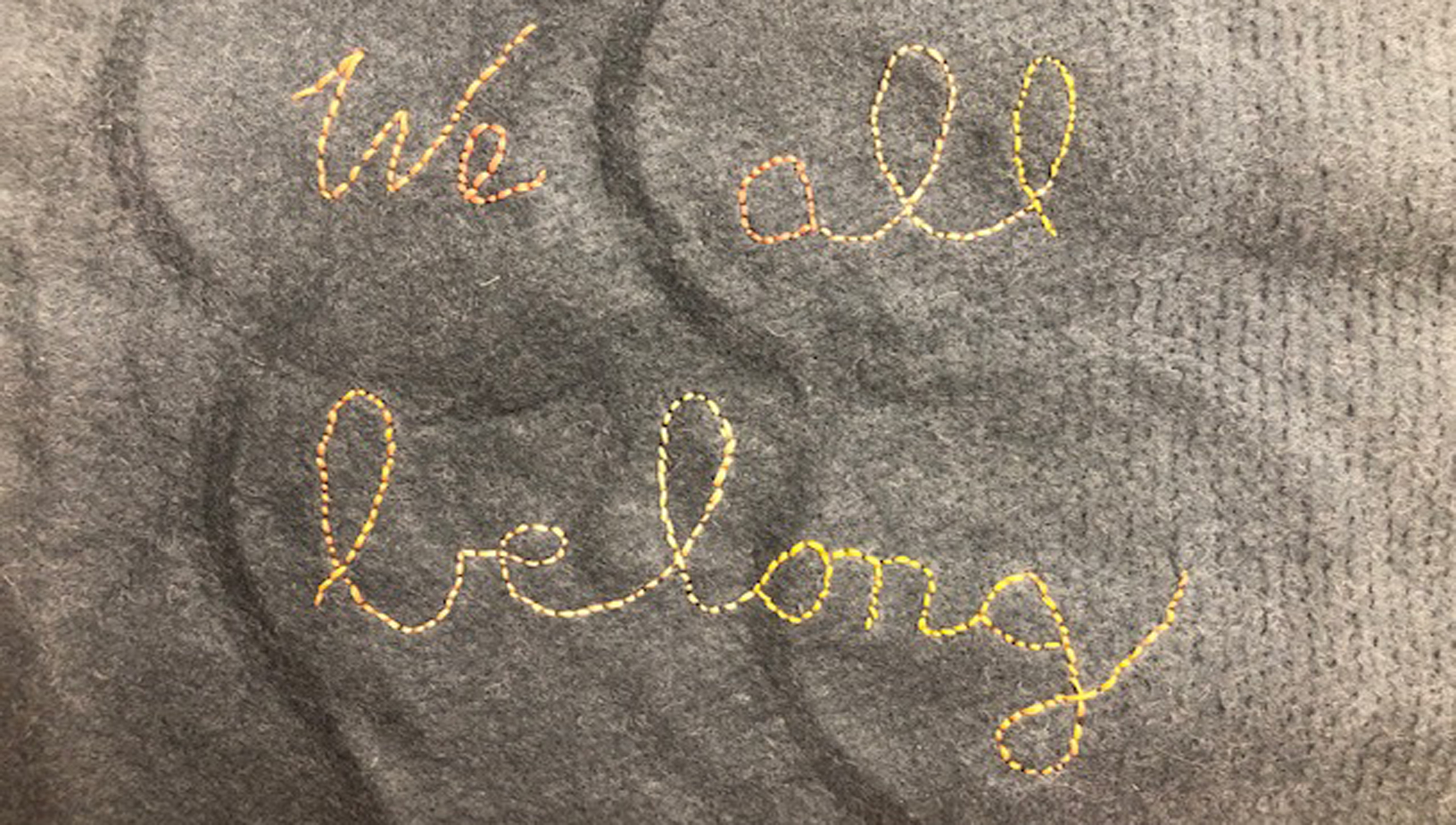 Textile that spells out "we all belong"