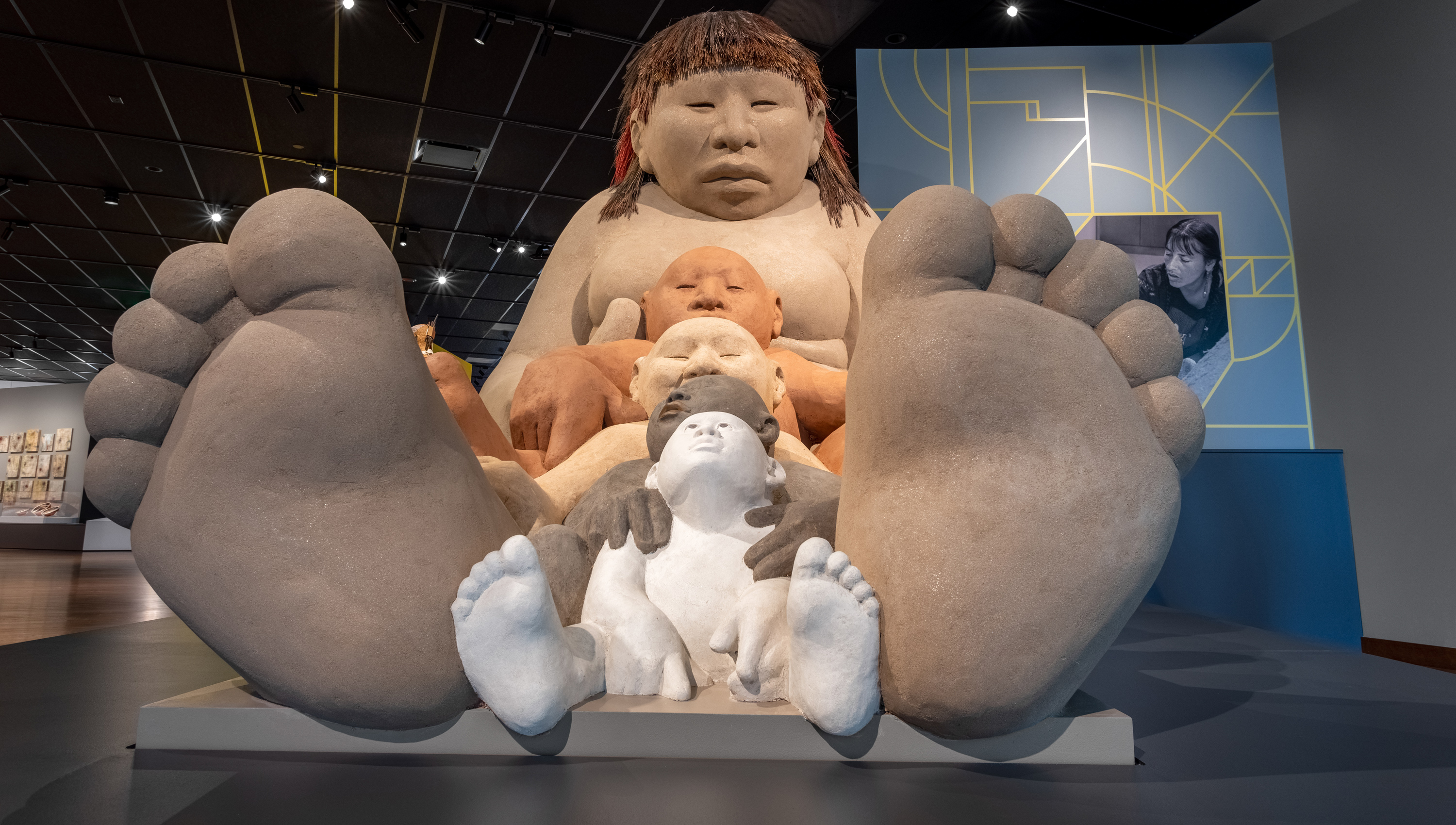 Large, tall clay sculpture in the shape of an Indigenous woman sitting down