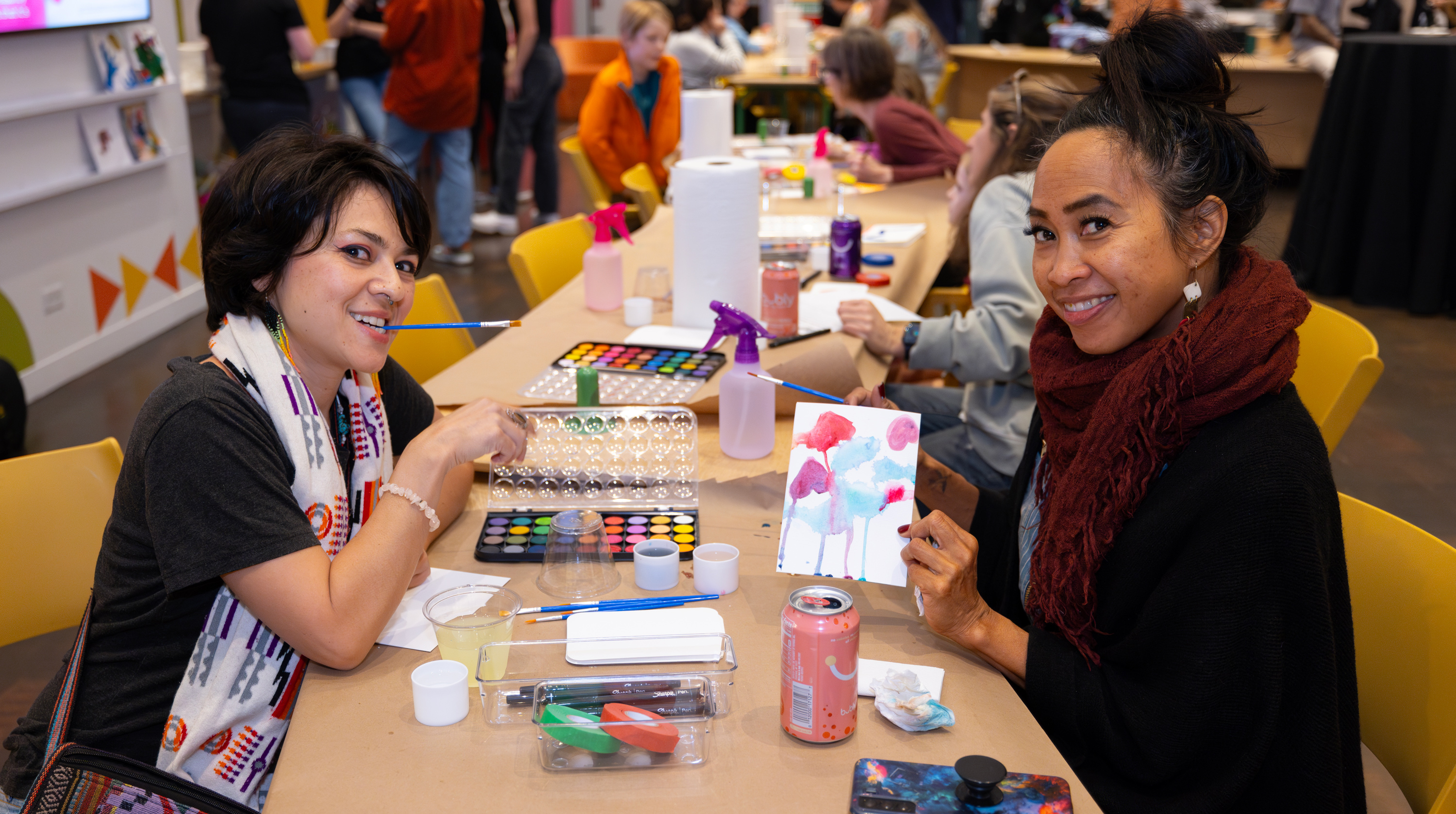 Two women educators holding up their art