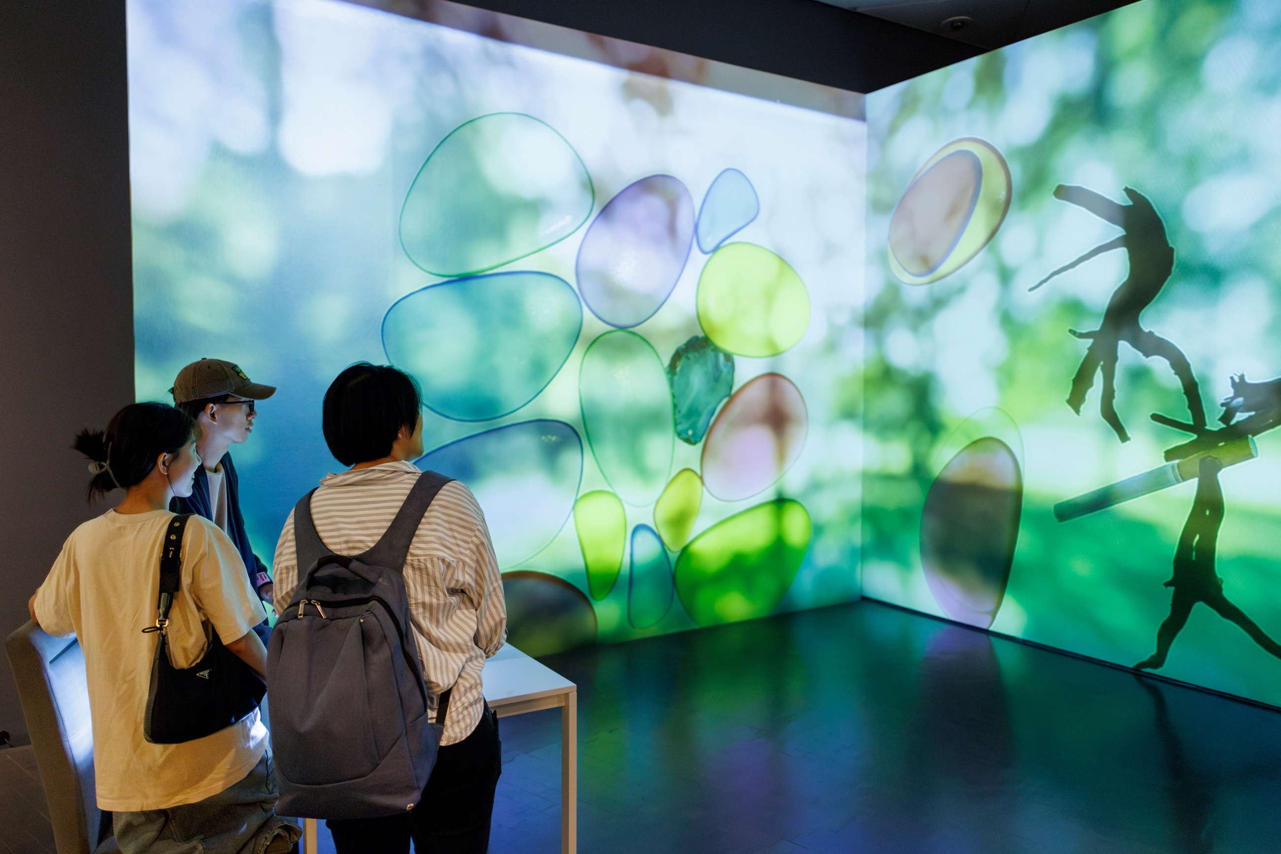 Three visitors in front of a color projection screen in the Alma Thomas exhibition