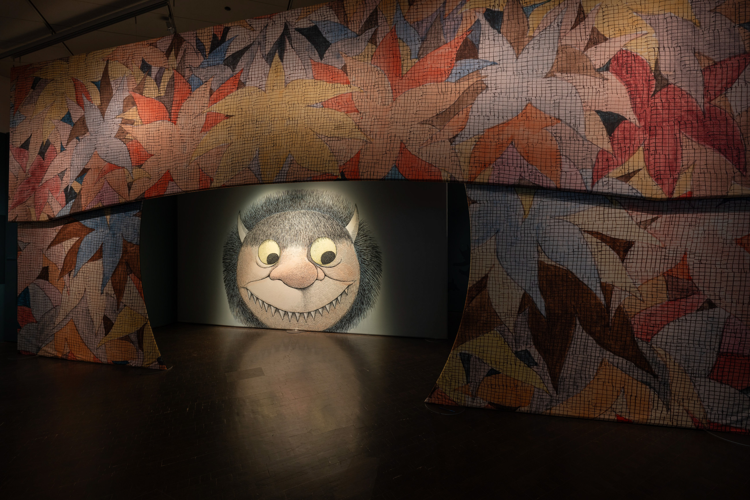 entrance to the Wild Things exhibition with leaf illustrations and large illustration of one of the monster faces Sendak drew