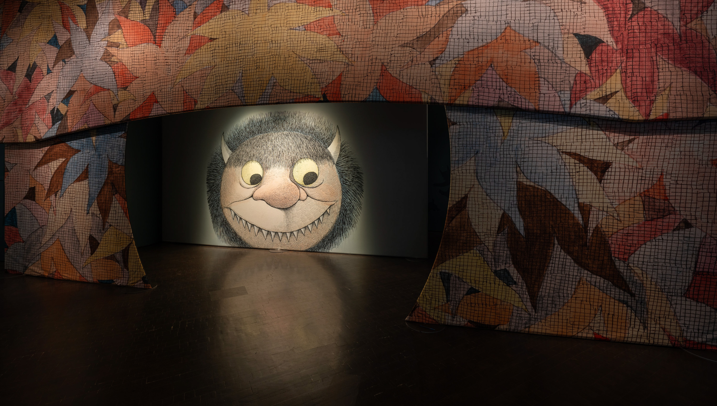 entrance to the Wild Things exhibition with leaf illustrations and large illustration of one of the monster faces Sendak drew