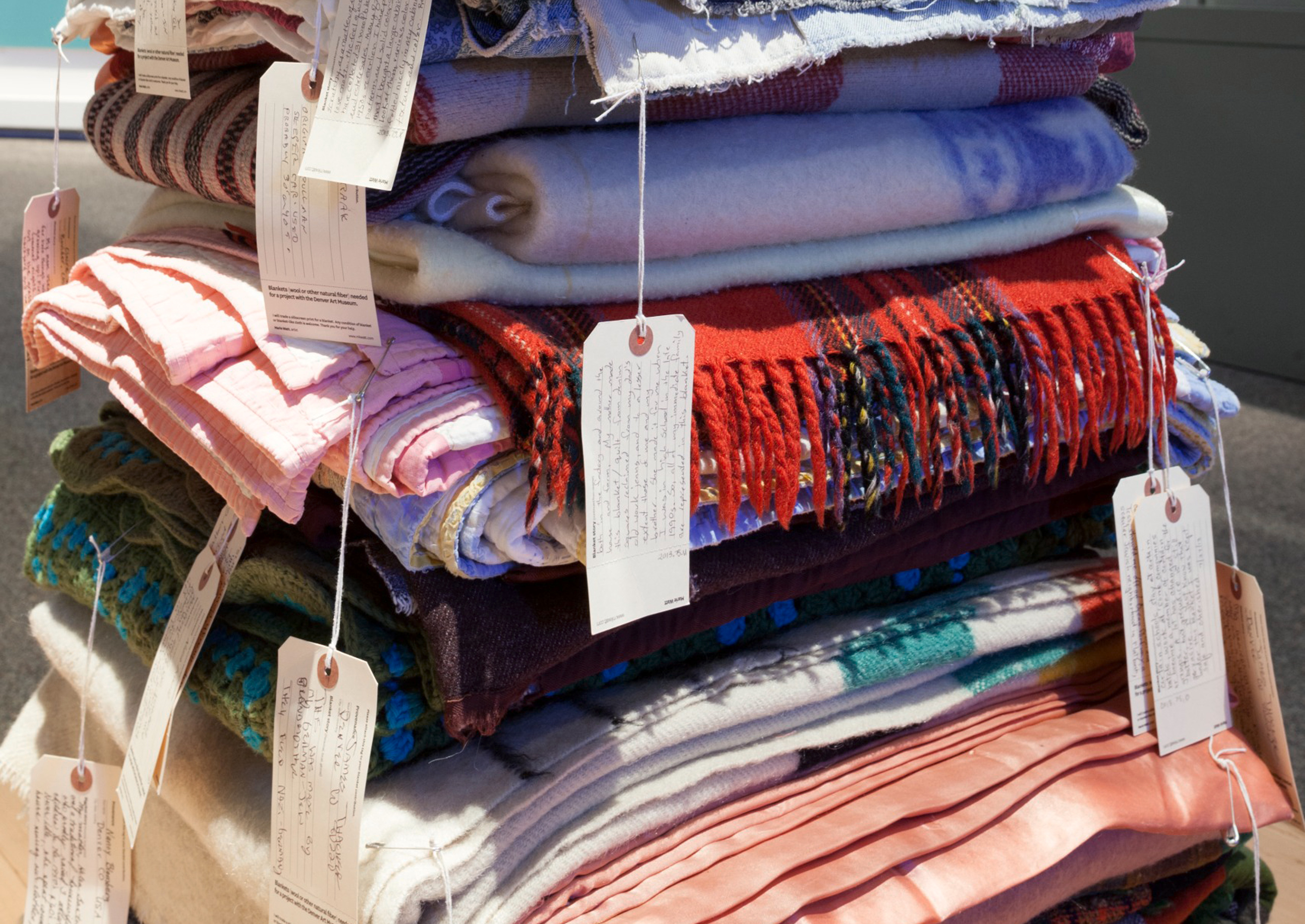 Close-up of a stack of blankets with white handwritten tag cards