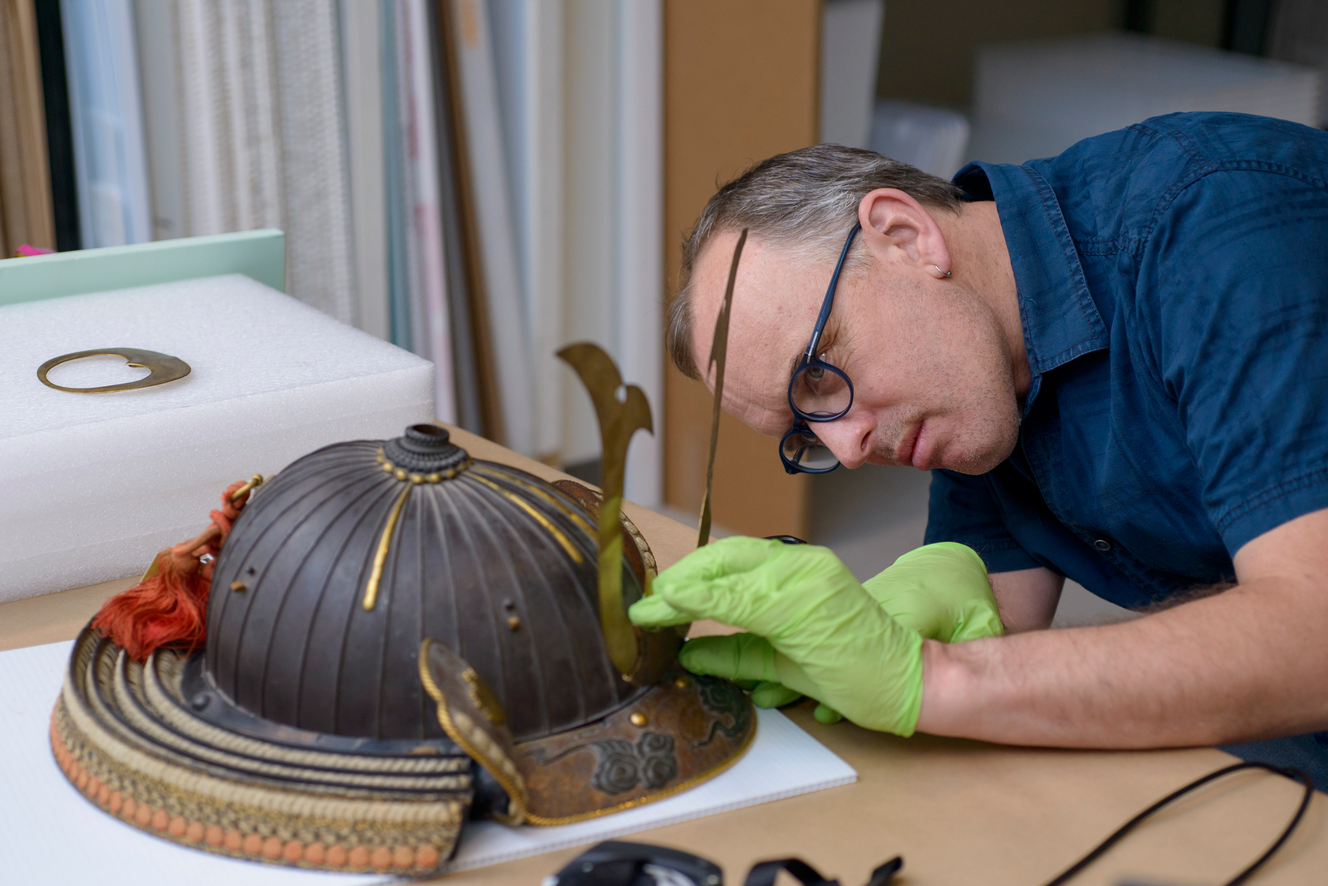 Man on museum staff conserving an ancient helmet