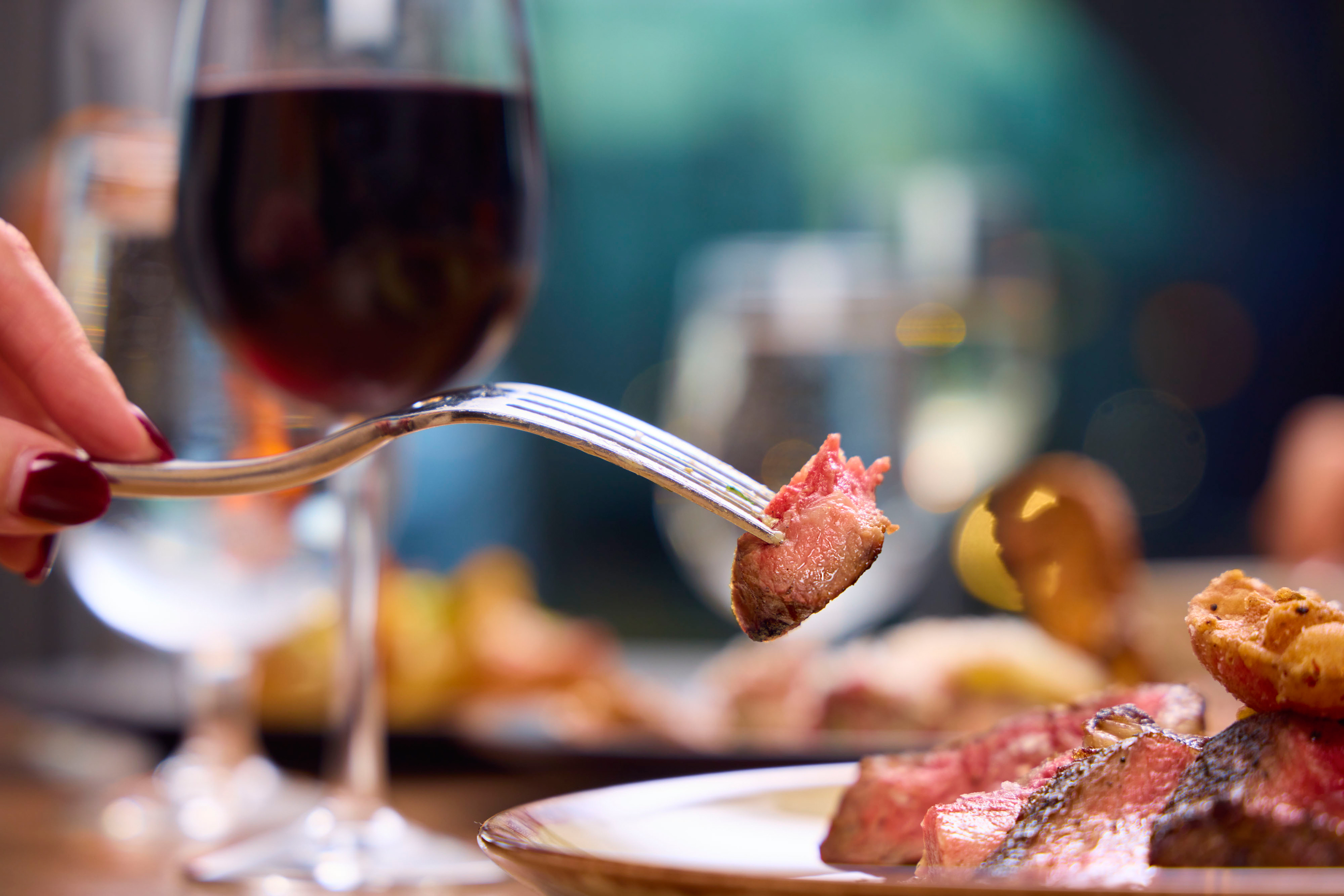 Close-up view of a person with a fork eating steak