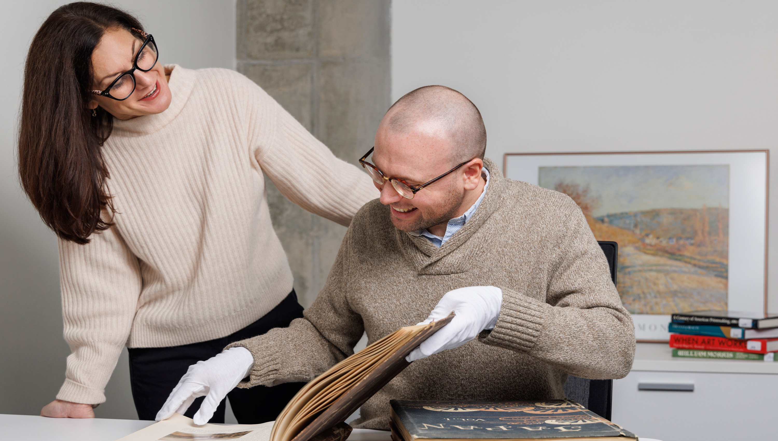 Woman and man pouring over a large book and research together
