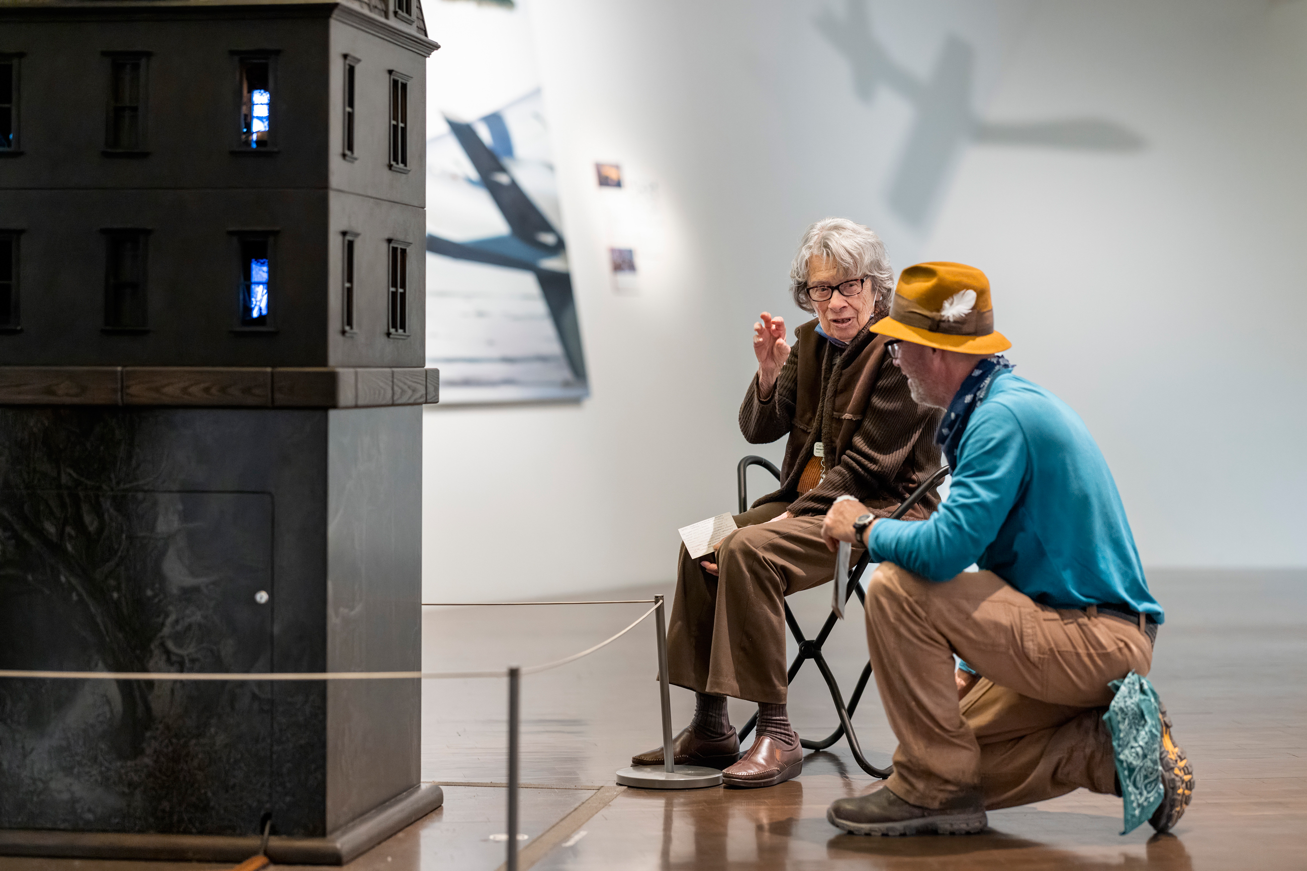 Two older visitors talking and examining a sculpture