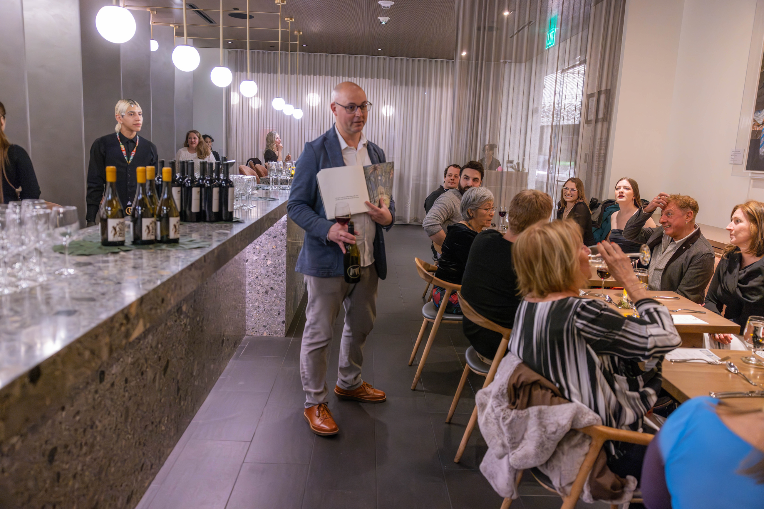 Large group of guests listening to somelier discuss menu