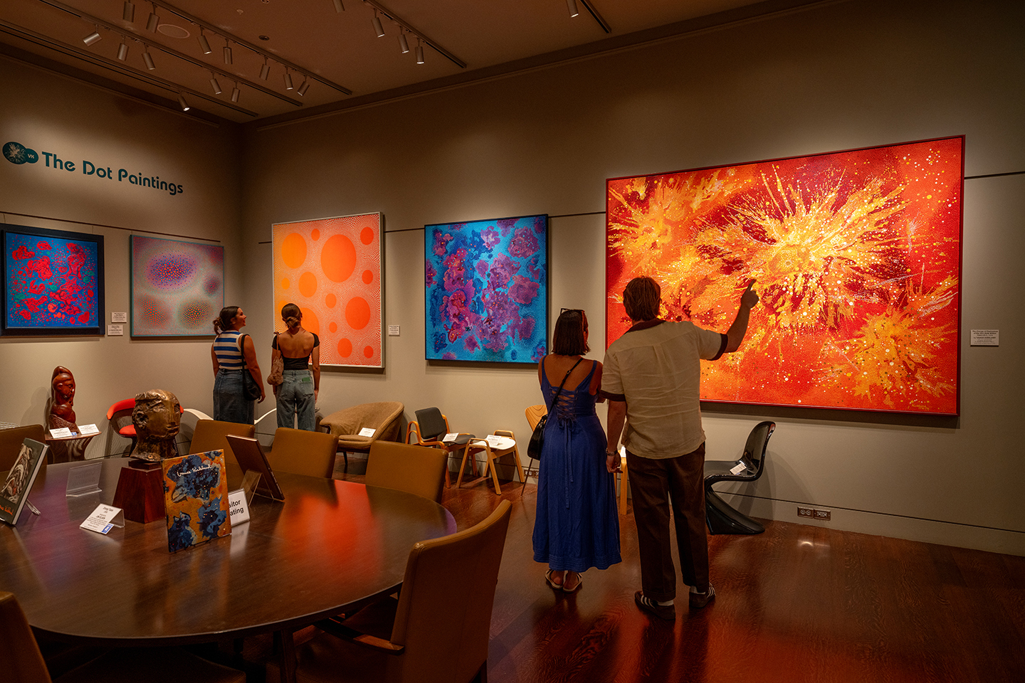 Four visitors looking at Vance Kirkland's colorful and vibrant abstract dot paintings