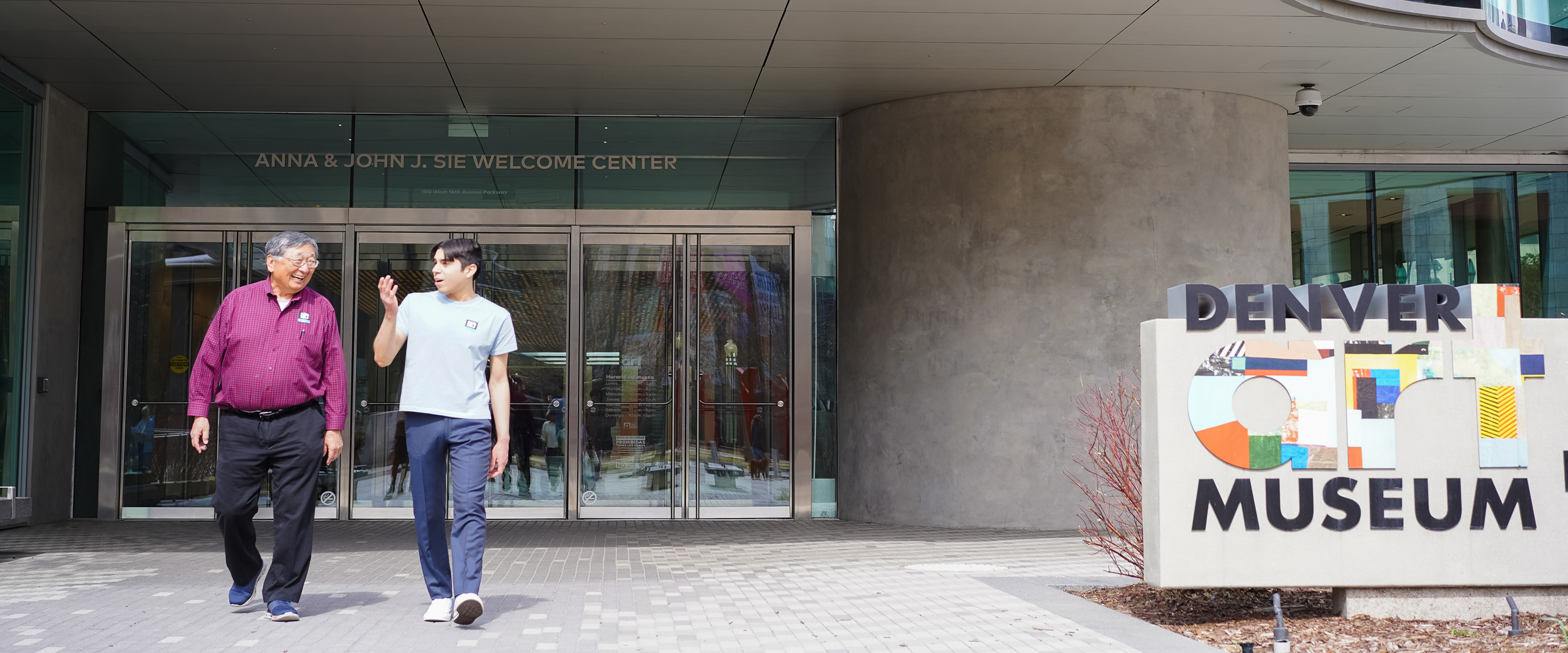 Two men talking and walking out of the museum entrance